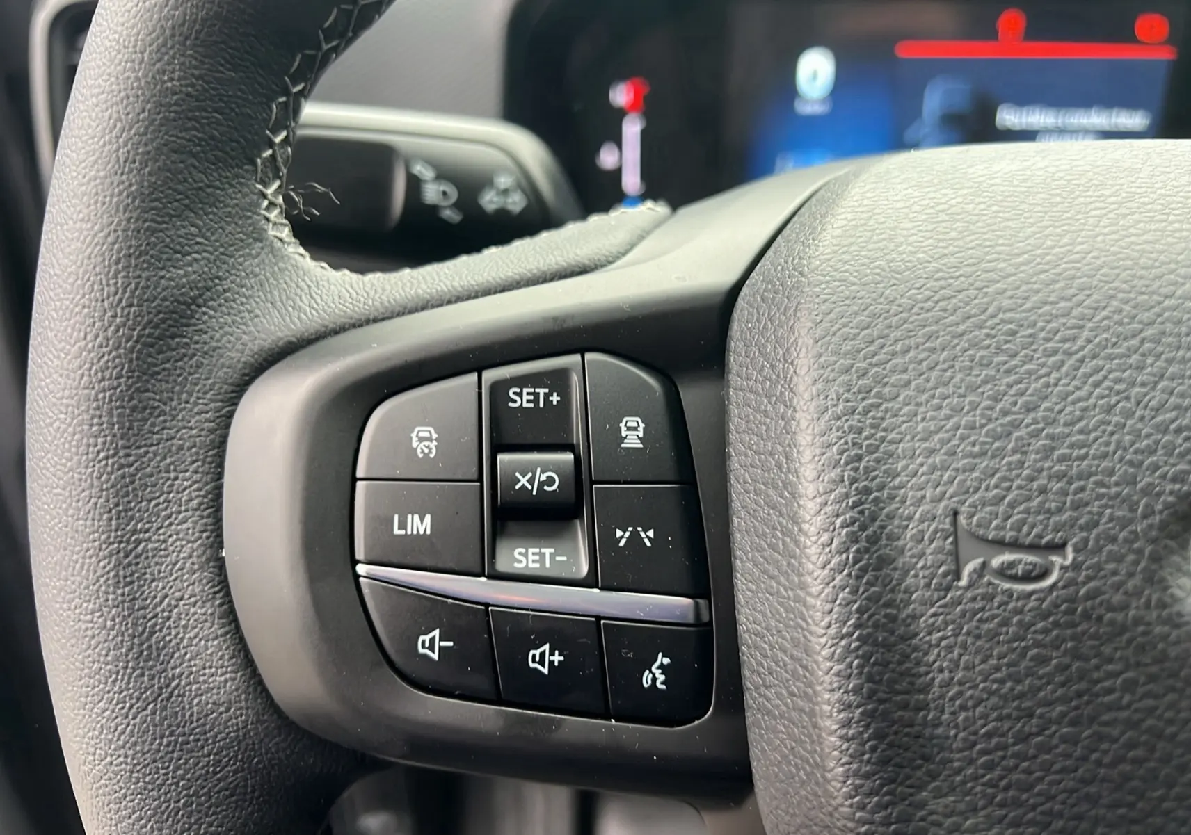 Gros plan sur le volant cuir multifonctions du Ford Ranger gris carbone, avec commandes de régulateur et audio visibles.