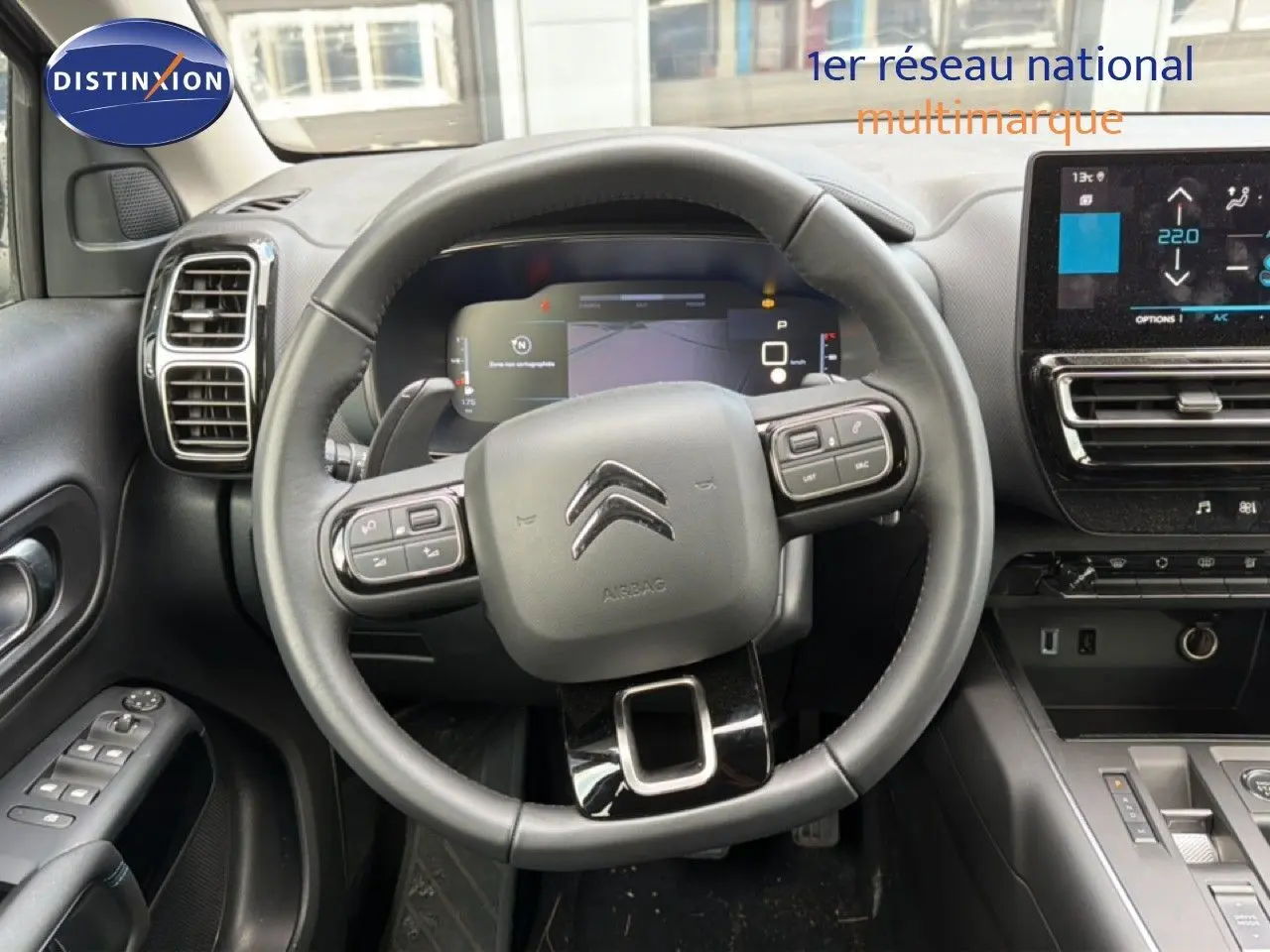 Vue intérieure centrée sur le volant noir du Citroën C5 Aircross 2025 avec tableau de bord digital et écran tactile.