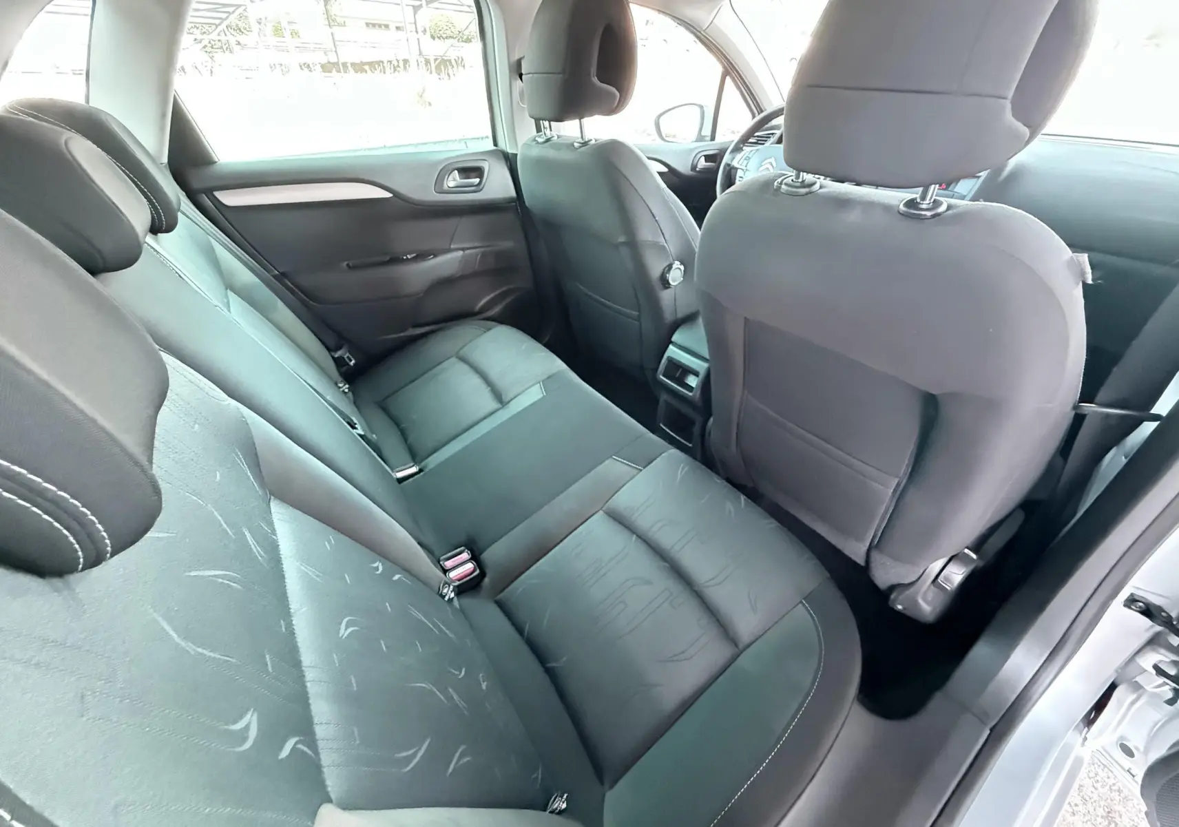 Vue intérieure arrière côté droit de la Citroën C4 gris, montrant les sièges tissu noir et l'espace passagers.
