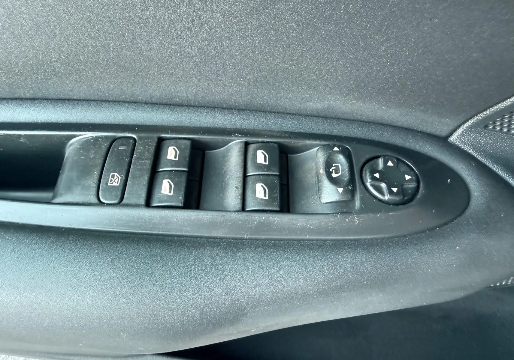Vue rapprochée des commandes de lève-vitres et réglage des rétroviseurs côté conducteur d'une Citroën C4 gris.