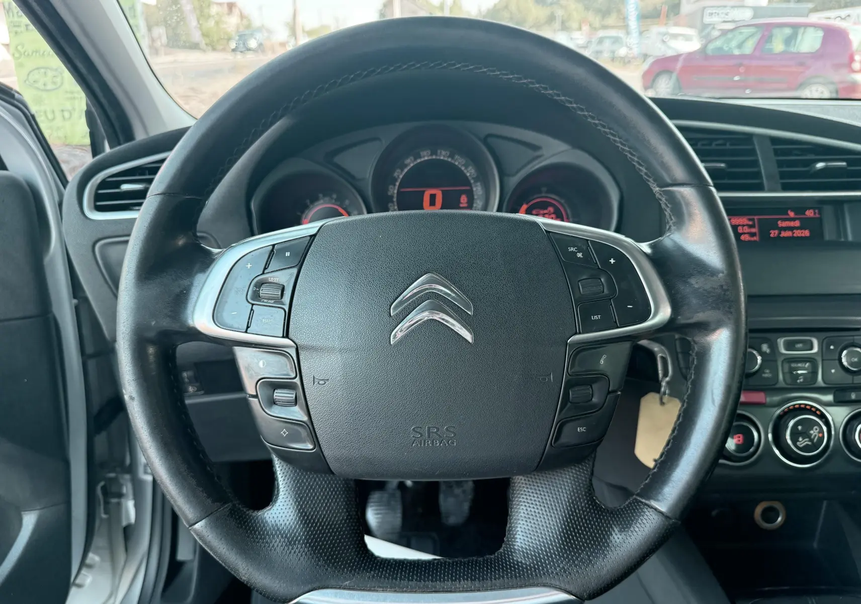 Vue rapprochée du volant noir de la Citroën C4 2011 avec commandes intégrées et tableau de bord en arrière-plan.
