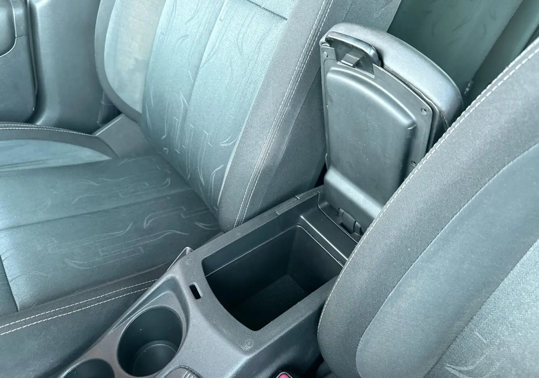 Vue rapprochée de l'intérieur noir en tissu du Citroën C4 2011, montrant la console centrale avec accoudoir ouvert.