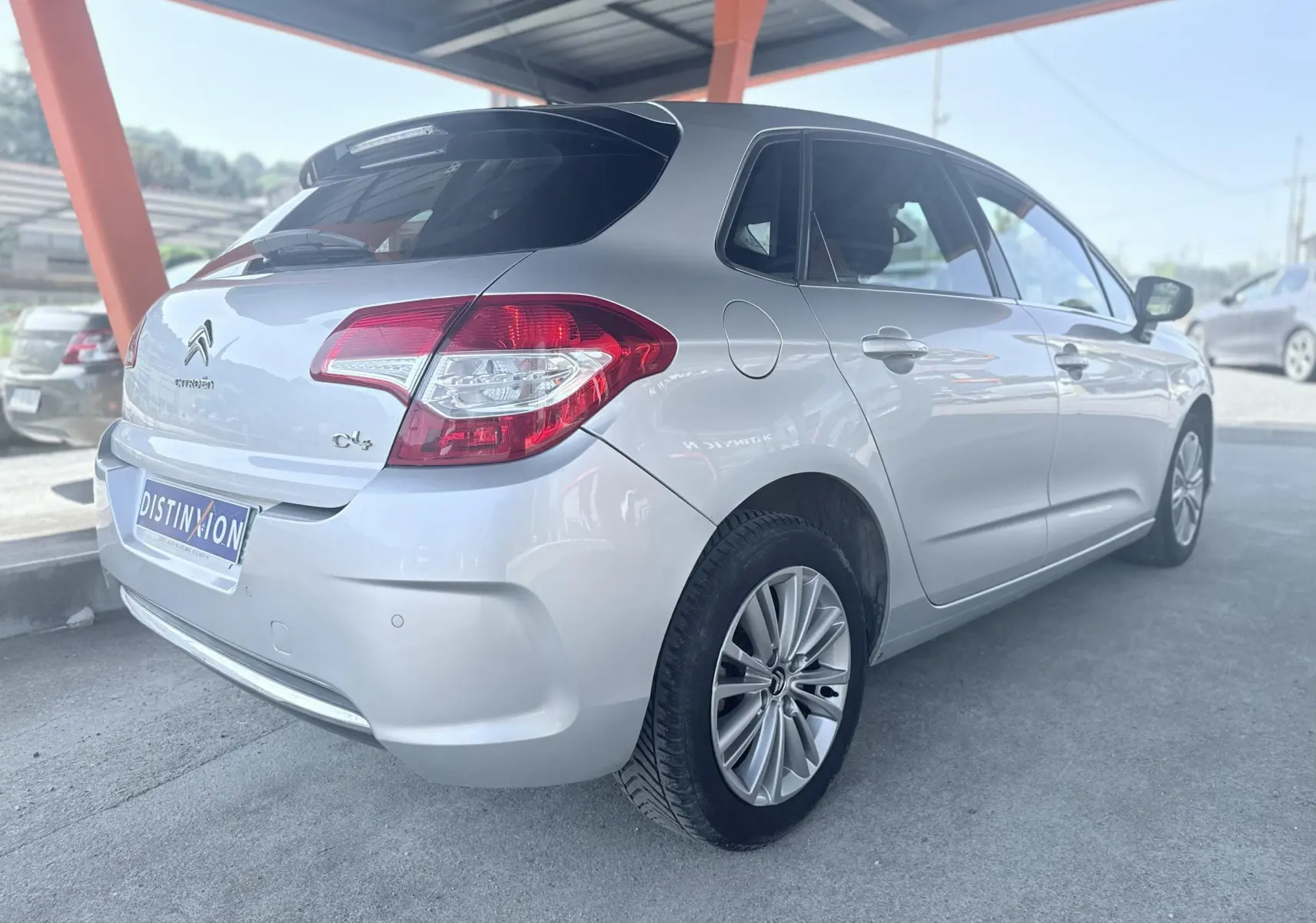 Vue 3/4 arrière droite d'une Citroën C4 gris clair, avec feux arrière distinctifs et jantes alliage.