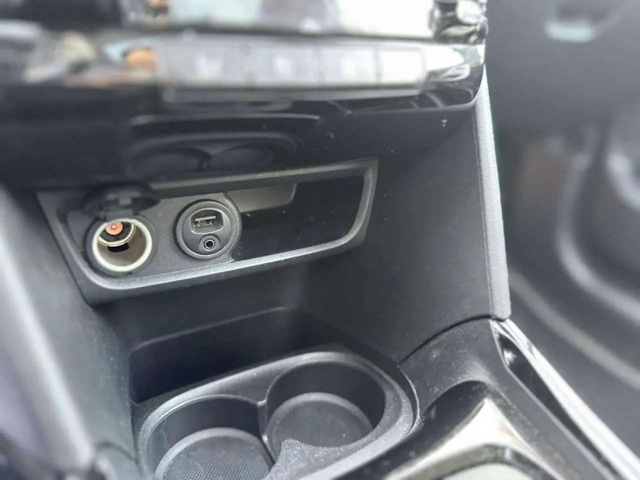 Gros plan sur la console centrale intérieure du Peugeot 2008 gris foncé, montrant prises USB et allume-cigare.