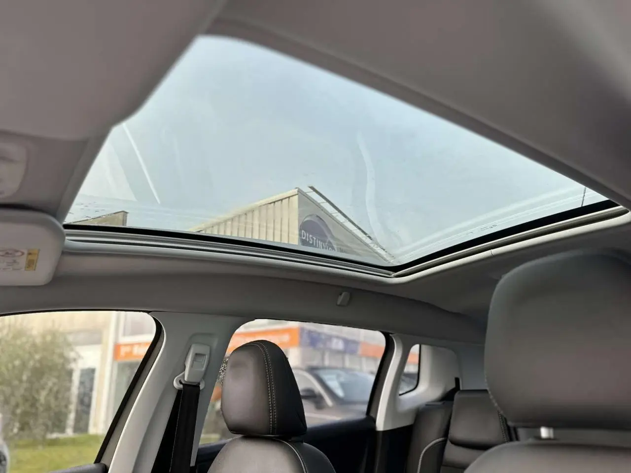Vue intérieure du toit vitré panoramique du Peugeot 2008 gris foncé, avec sièges avant en cuir noir visibles.