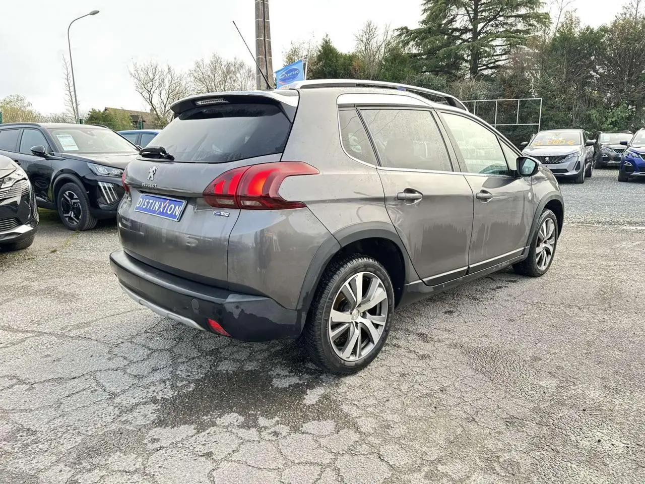 Peugeot 2008 gris foncé vue 3/4 arrière droit, avec jantes aluminium 17'' et coques de rétroviseurs chrome brillant.