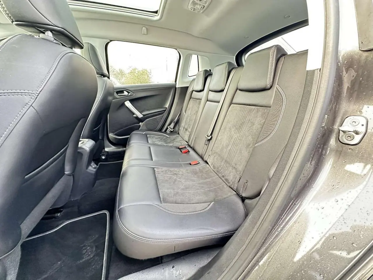 Vue intérieure côté droit sur la banquette arrière en cuir et alcantara du Peugeot 2008 gris foncé avec toit panoramique.