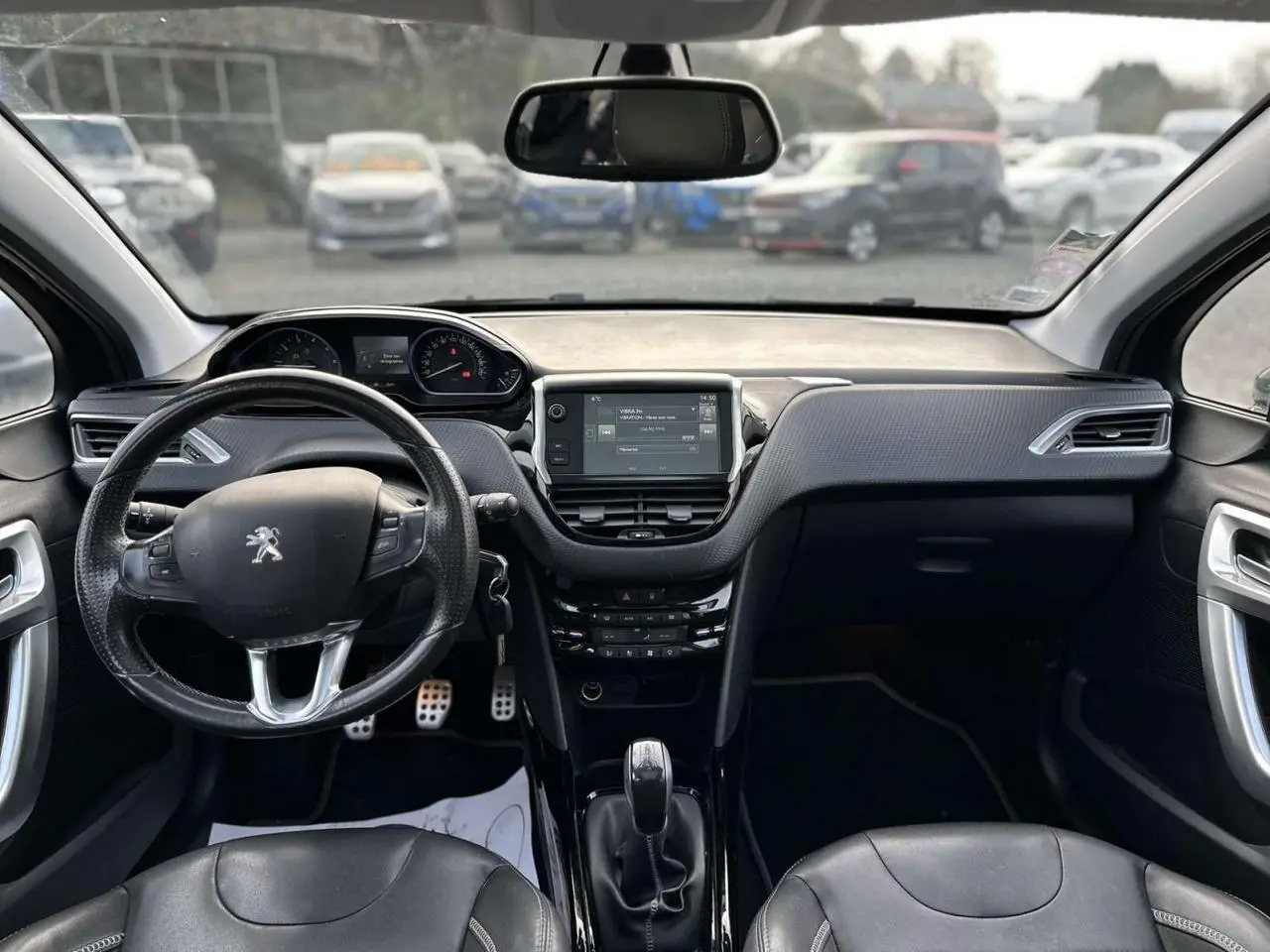 Vue frontale de l'habitacle du Peugeot 2008 gris foncé, avec volant cuir multifonction et écran tactile central.