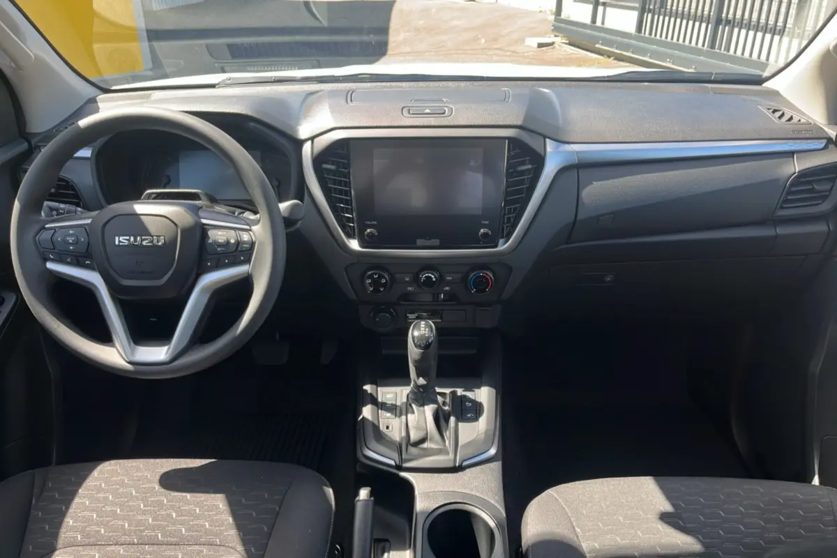 Vue intérieure frontale de l'Isuzu D-MAX 2026 avec tableau de bord noir et écran tactile central éteint.