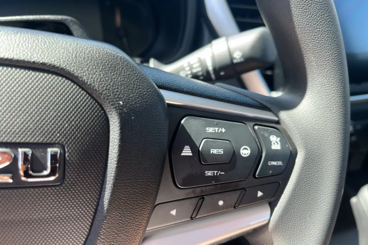 Gros plan sur le volant multifonctions noir de l'Isuzu D-MAX 2.2 TD 164 Space Evolution avec commandes de régulateur de vitesse.