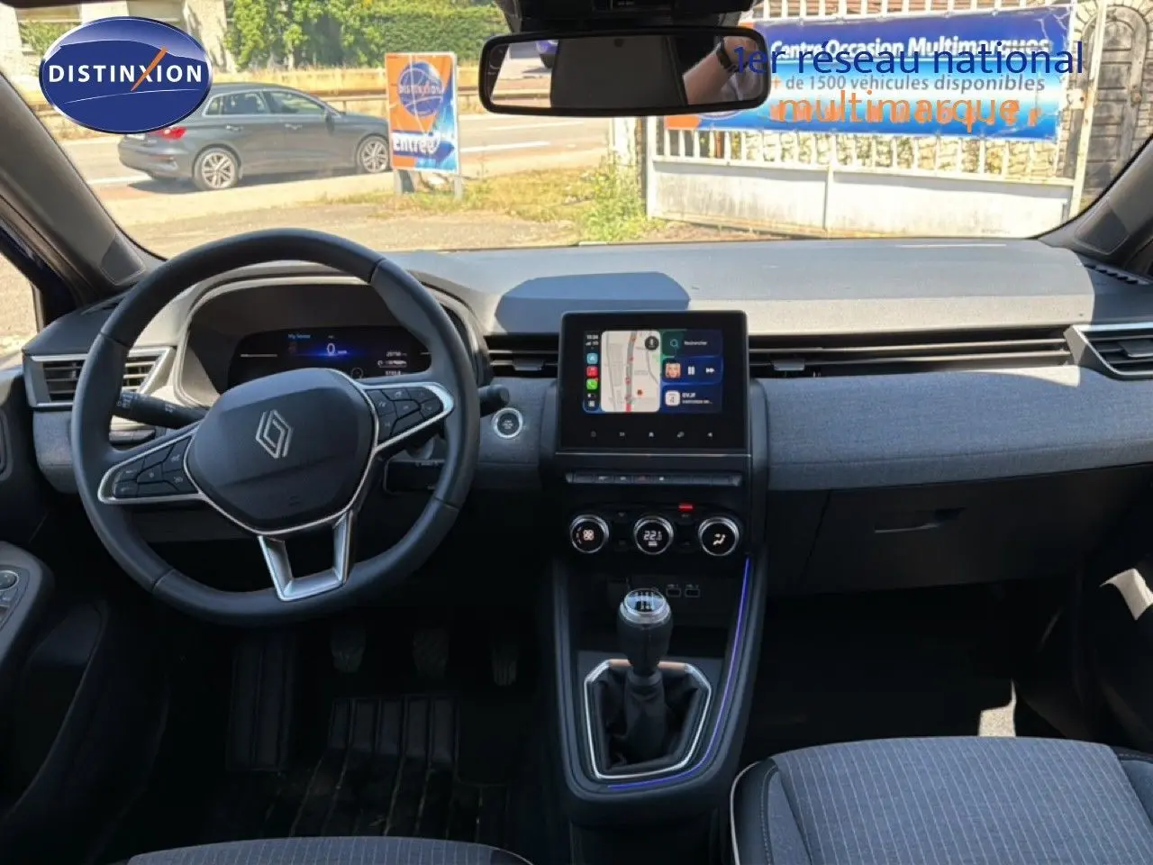 Vue intérieure frontale du tableau de bord de la Renault Clio 2025, volant multifonction et écran tactile central.