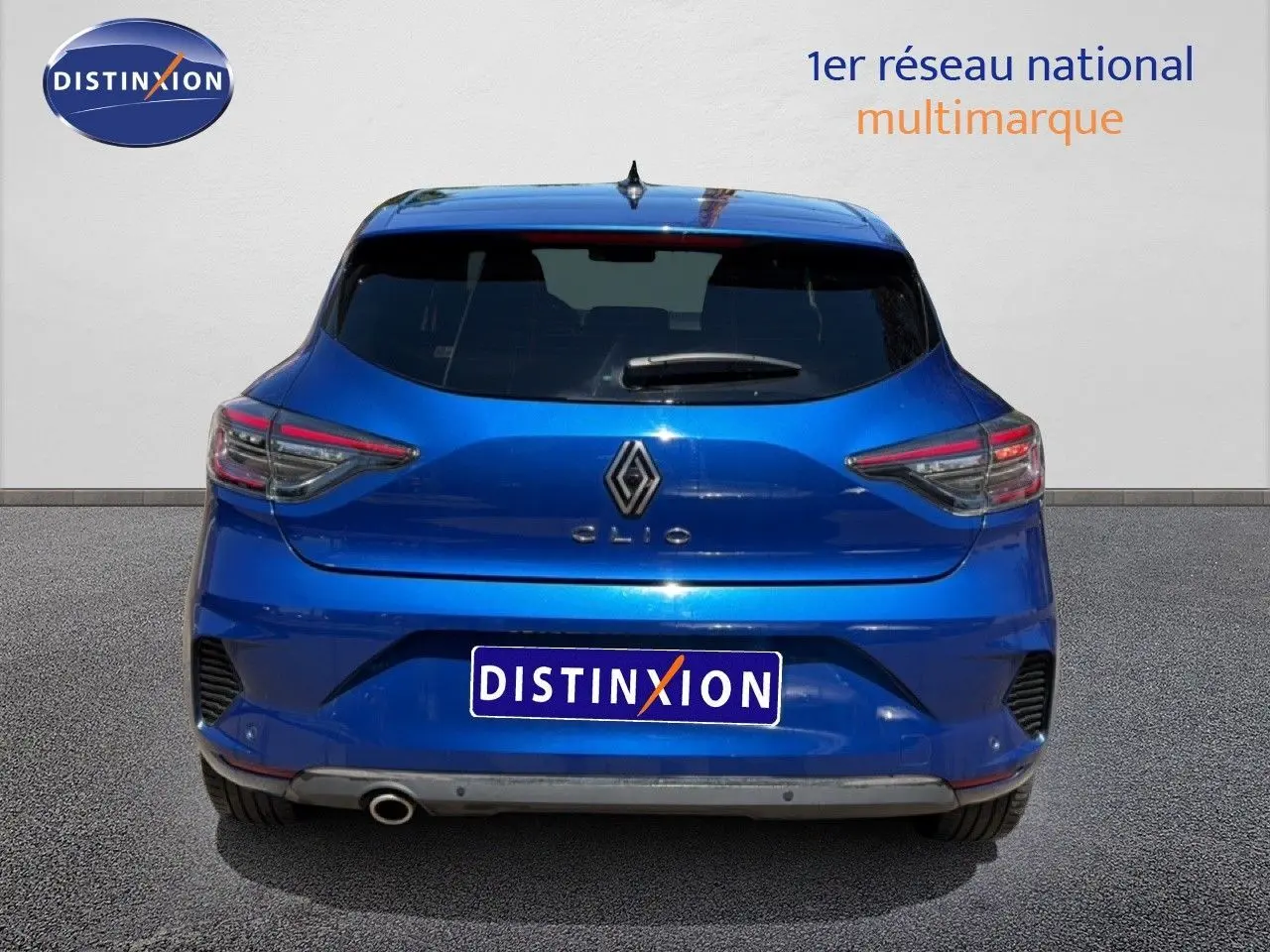 Vue arrière d'une Renault Clio 2025 bleu iron metal avec feux arrière LED et sortie d'échappement visible côté gauche.