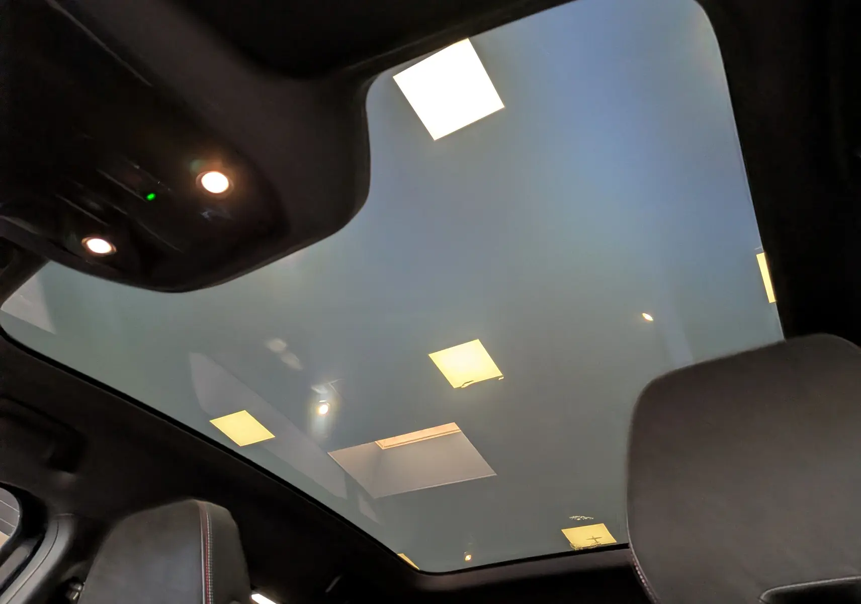 Toit panoramique en verre vu de l'intérieur arrière du Renault Rafale noir étoilé, éclairage intérieur visible.