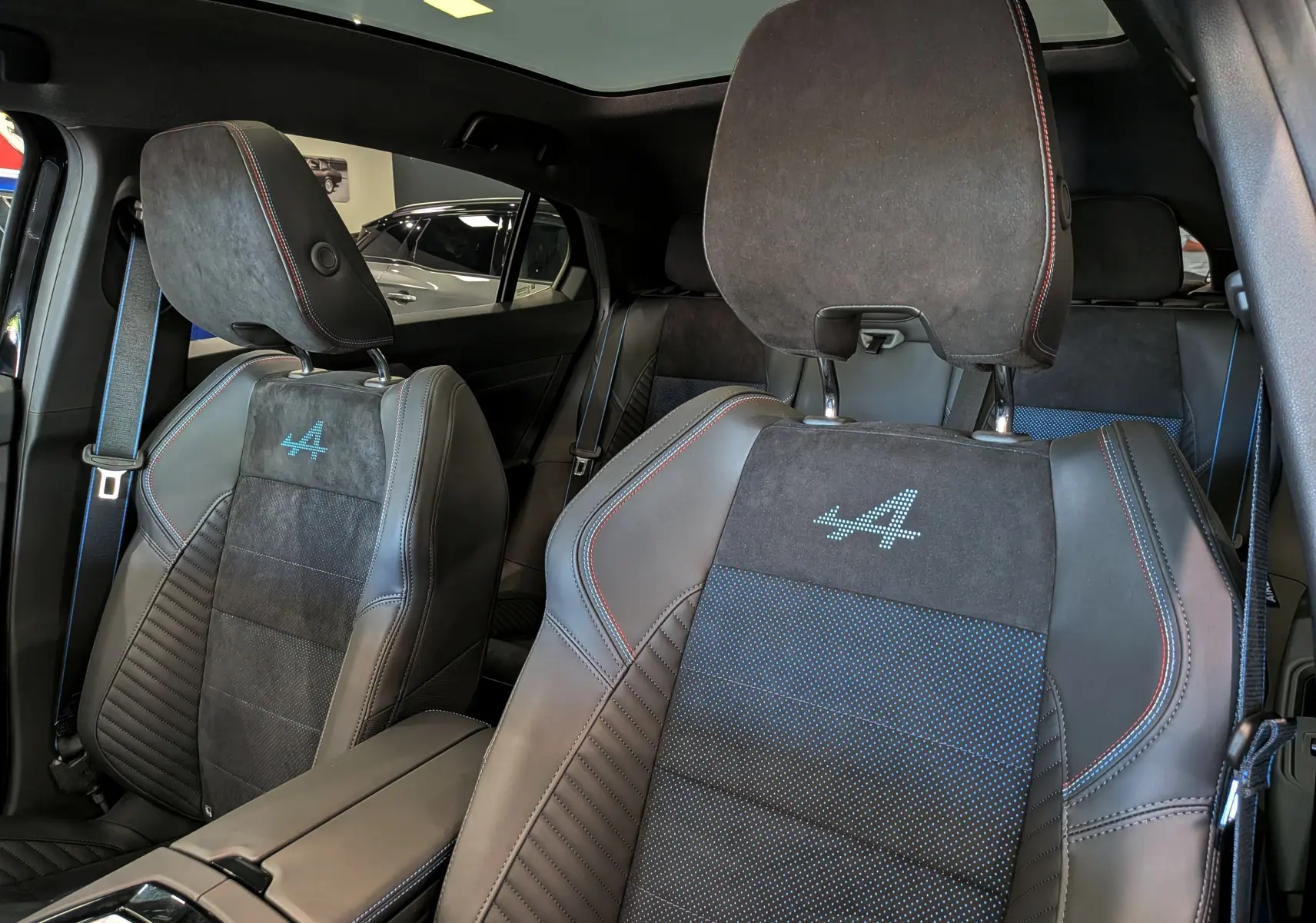 Vue intérieure rapprochée des sièges avant en cuir noir et alcantara avec logo Alpine brodé sur Renault Rafale 2026.