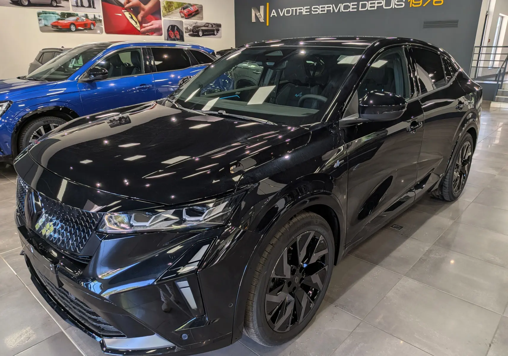 Vue 3/4 avant droite du Renault Rafale noir étoilé, soulignant ses jantes noires et son design sportif intérieur showroom.