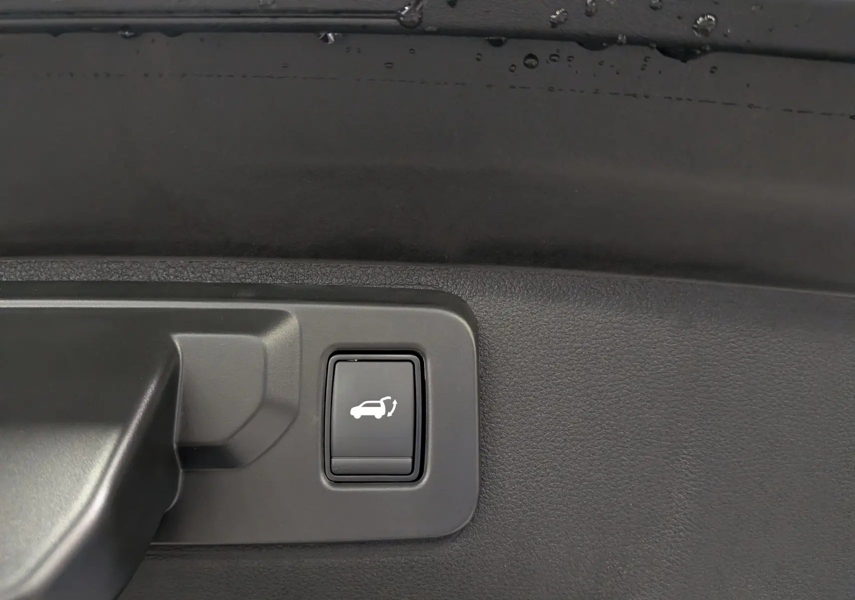 Bouton d'ouverture électrique du coffre sur panneau intérieur noir d'une Renault Rafale Hyper Hybrid 2026.