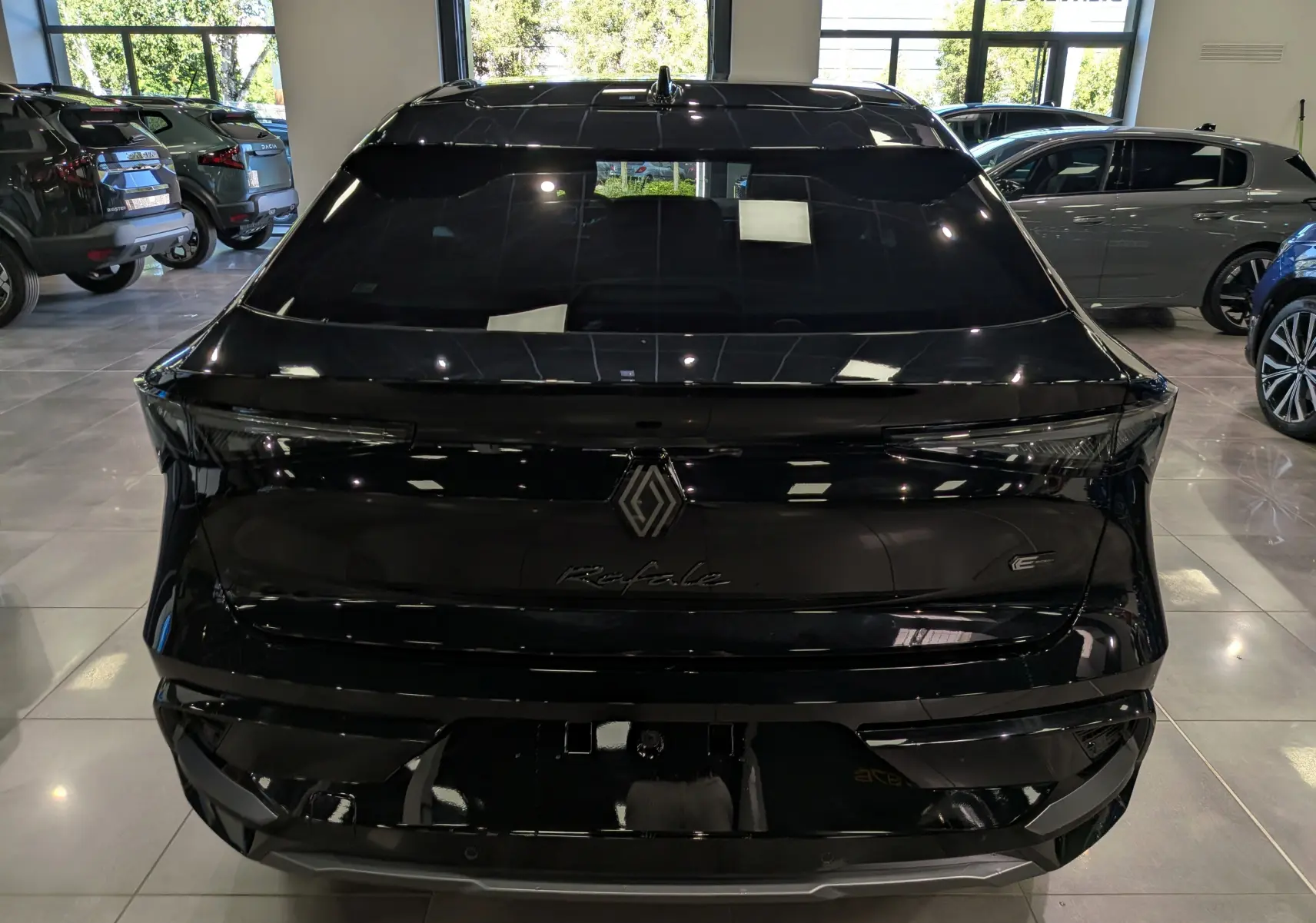Vue arrière d'une Renault Rafale noire étoilé, soulignant son design épuré et ses feux arrière fins en intérieur showroom.