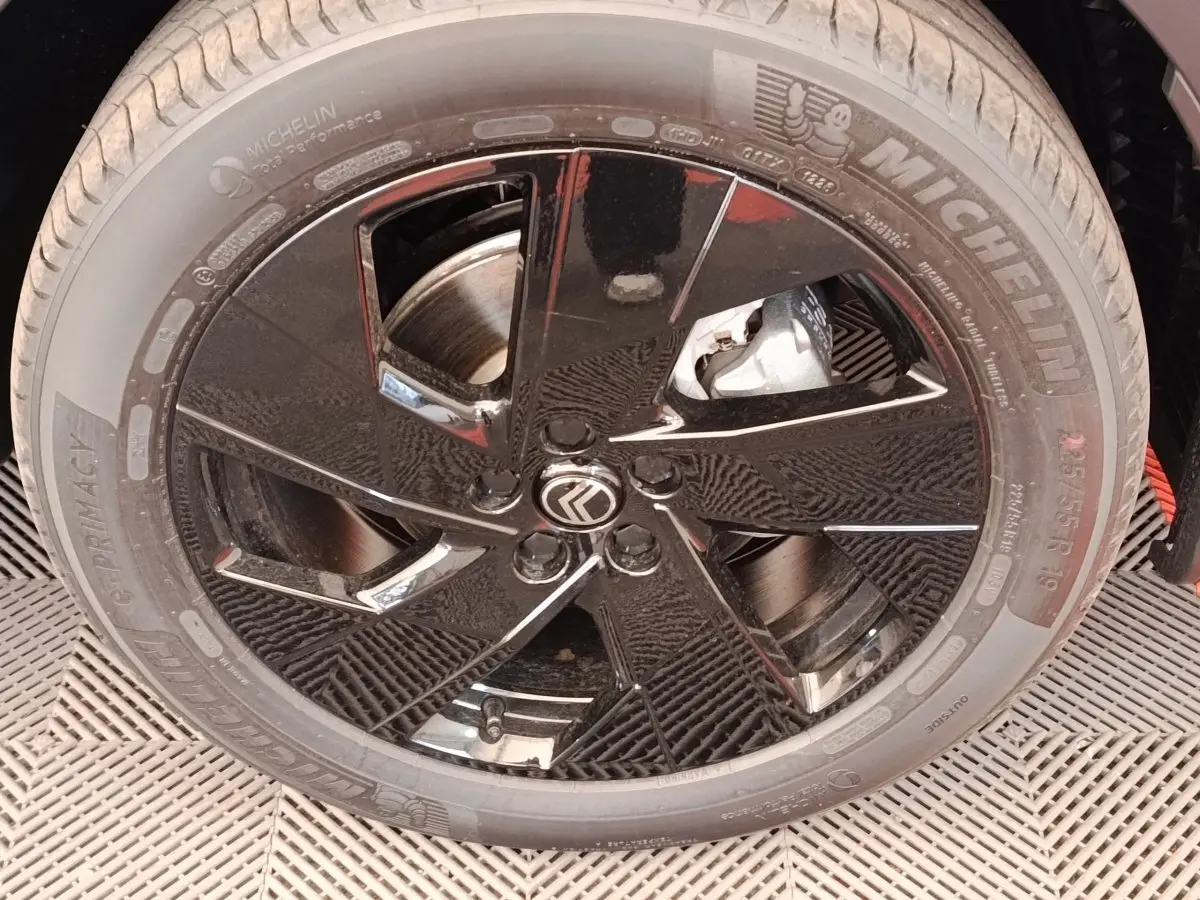 Gros plan sur la roue avant droite noire brillante d'une Citroën C5 Hybride 2026 avec logo Citroën au centre.