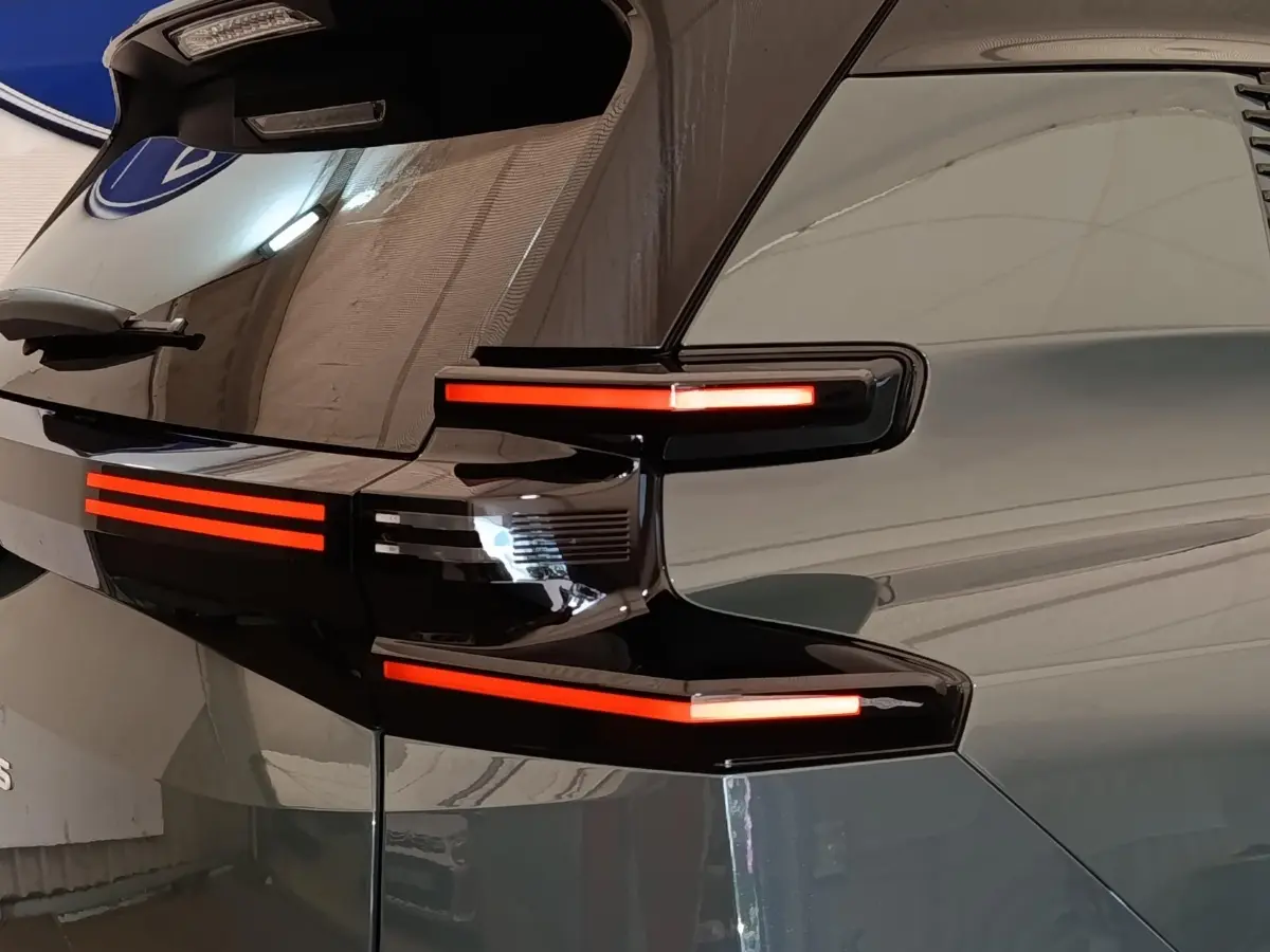 Feu arrière droit allumé d'une Citroën C5 hybride 2026 vert, vue en gros plan sur le hayon et la lunette arrière.