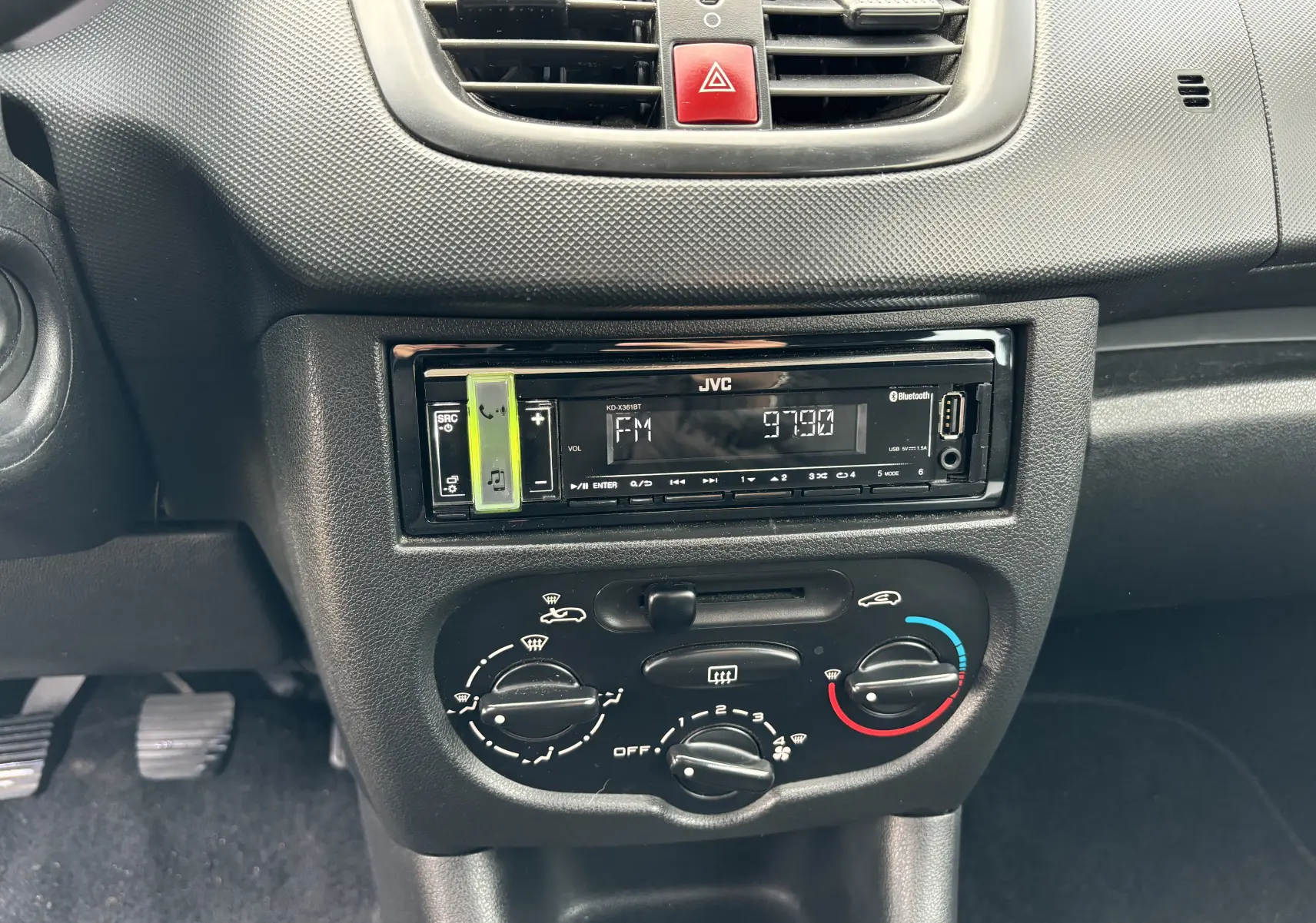Détail de la console centrale d'une Peugeot 206+ gris foncé de 2009, montrant l'autoradio JVC et les commandes de climatisation.