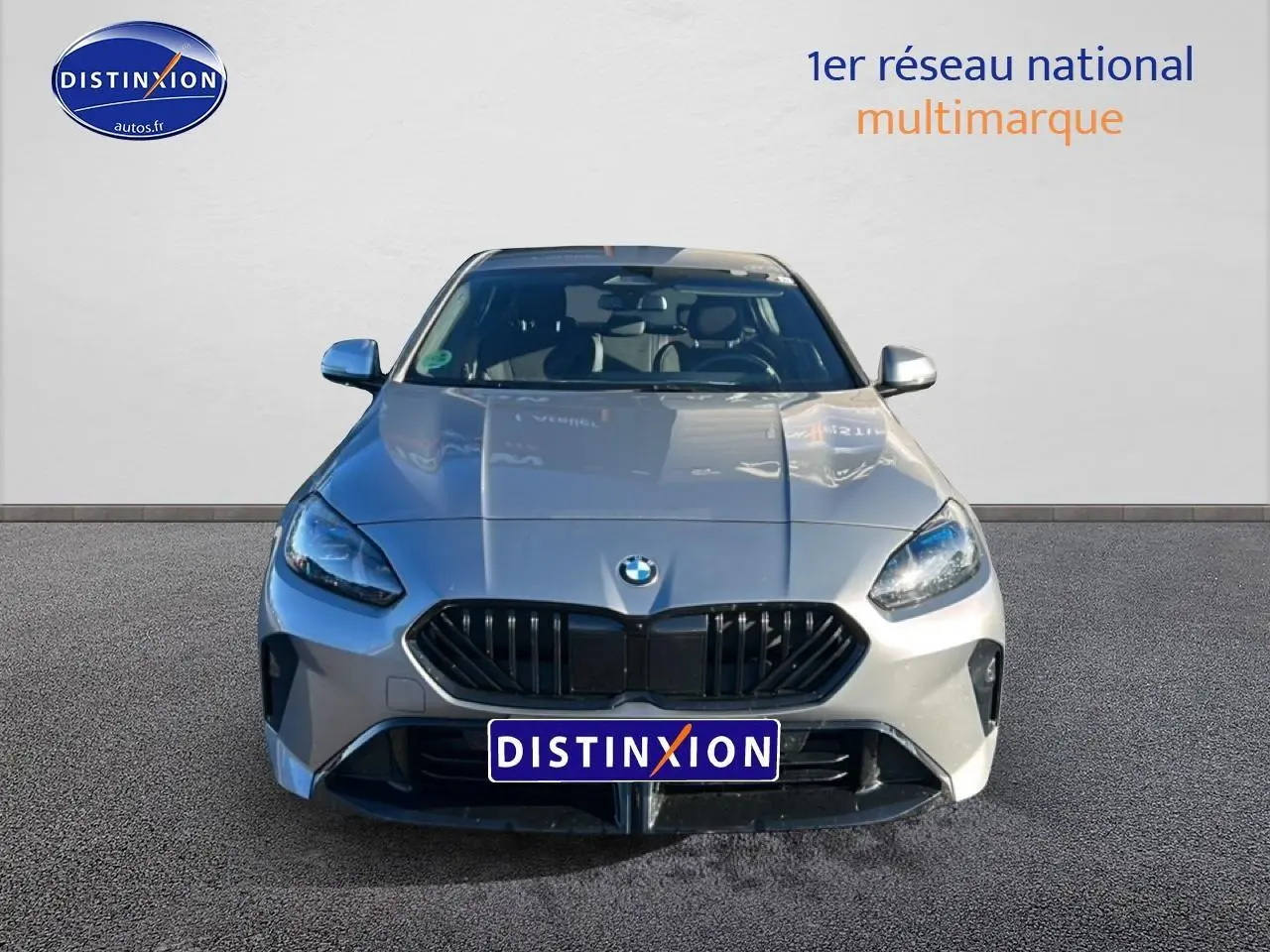 Vue frontale d'une BMW Série 1 118da gris Skyscraper avec calandre noire et phares LED allumés.