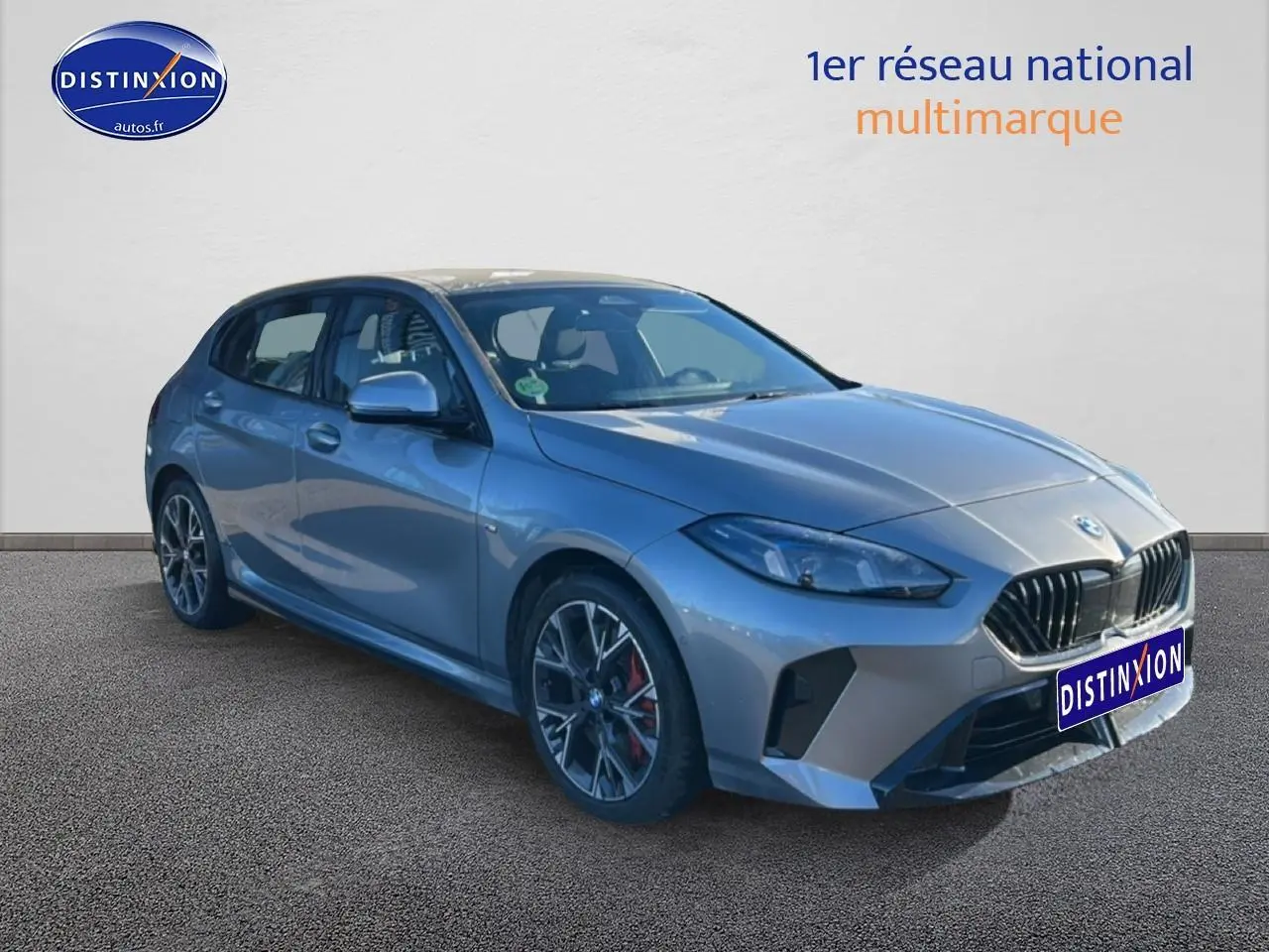 BMW Série 1 gris Skyscraper vue 3/4 avant droit avec jantes 18 pouces bicolores et calandre M Sport.