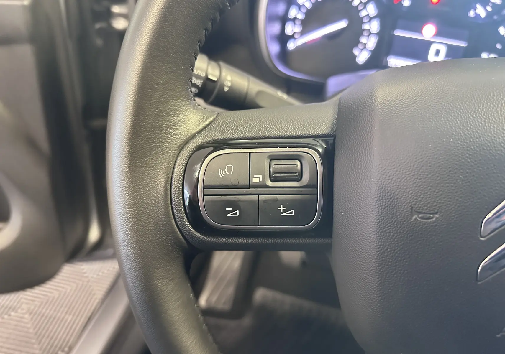 Gros plan sur le volant cuir noir de la Citroën C3 Aircross 2024 avec commandes audio intégrées.