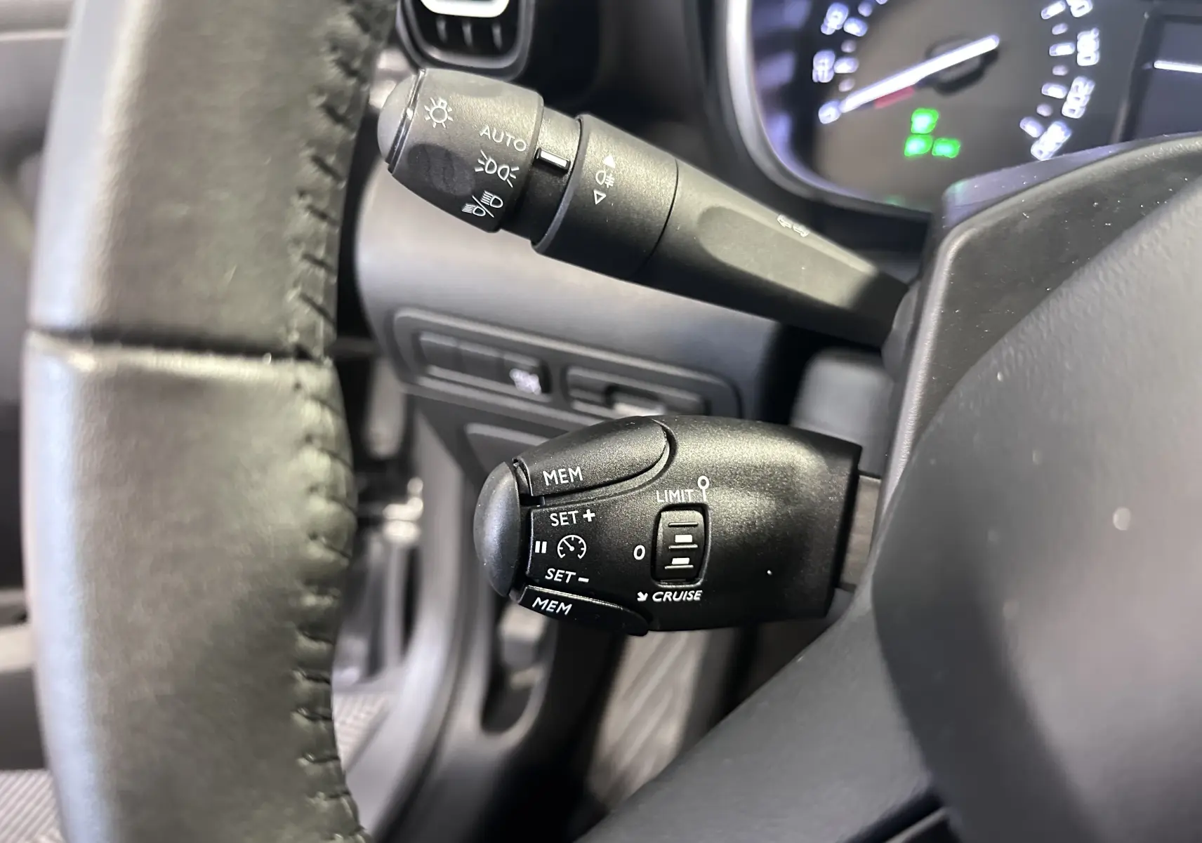 Gros plan sur le volant cuir et les commandes de régulateur de vitesse du Citroën C3 Aircross 2024, intérieur noir.