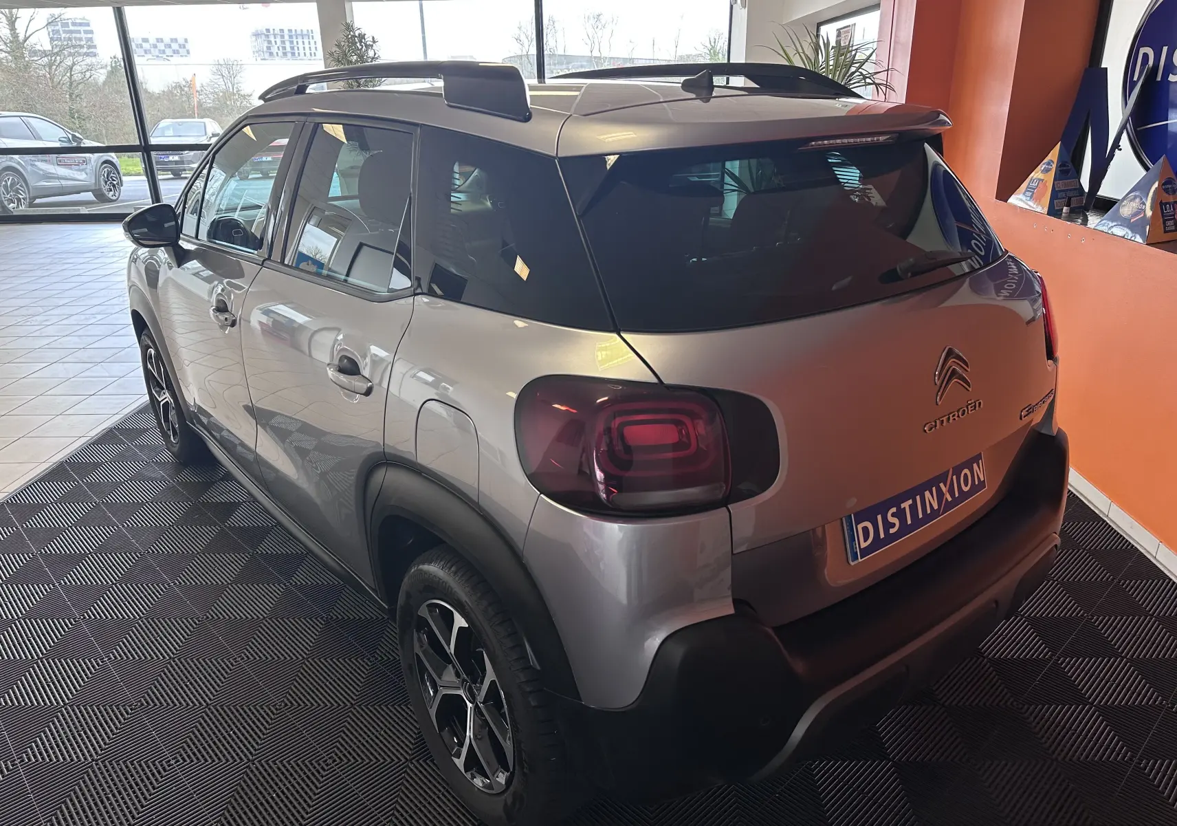 Vue 3/4 arrière droite d'une Citroën C3 Aircross gris Artense avec jantes alliage 16 pouces et vitres surteintées.