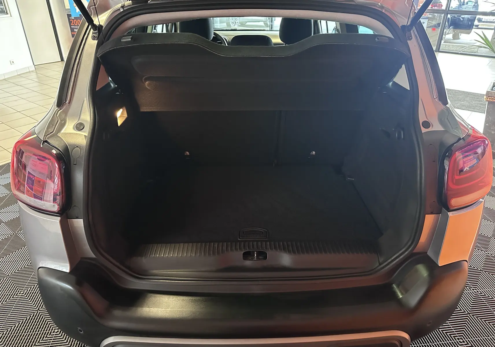 Coffre ouvert vu de l'arrière d'un Citroën C3 Aircross gris Artense 2024, intérieur spacieux et bien éclairé.