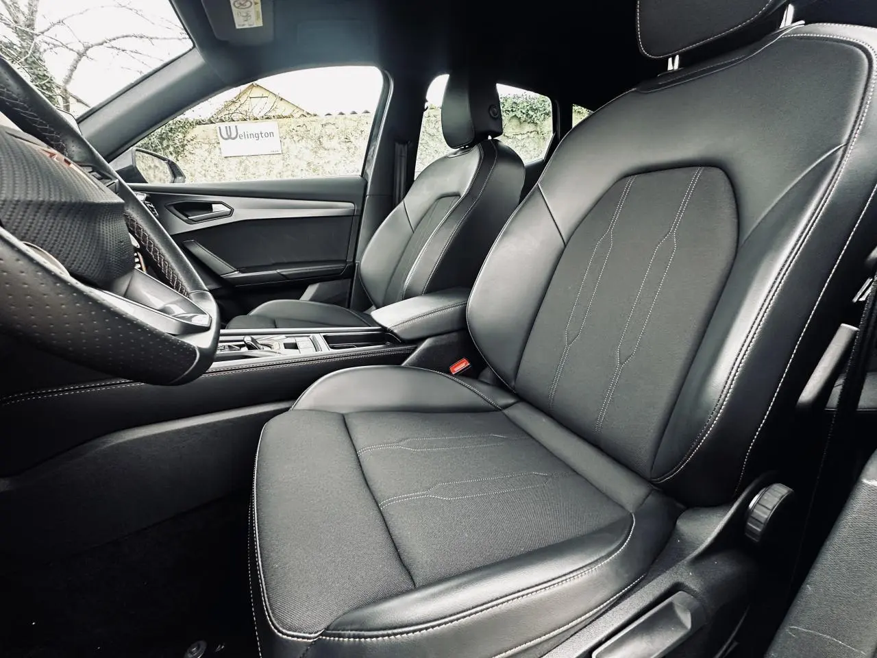 Vue intérieure côté conducteur du CUPRA Formentor 2.0 TDI 2025, sièges sports bimatière noirs avec surpiqûres blanches.