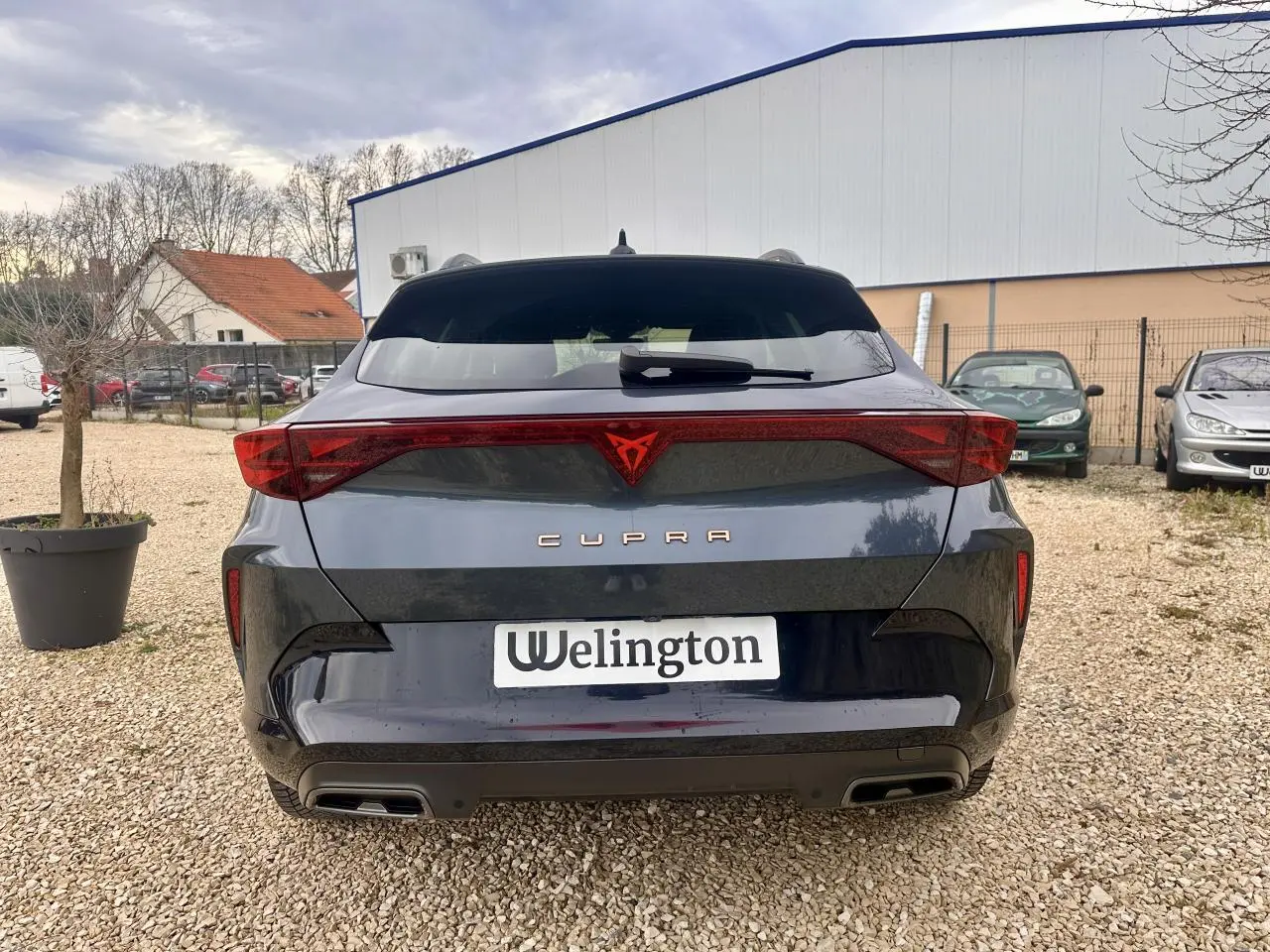 Vue arrière d'un CUPRA Formentor gris 2025 avec feux triangulaires et double sortie d'échappement intégrée.
