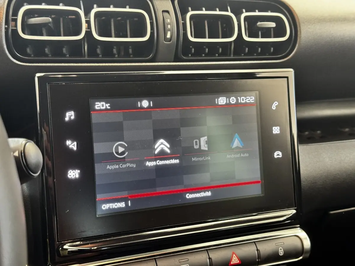 Écran tactile central de 7 pouces dans l’habitacle gris foncé d’une Citroën C3 PureTech 110 Shine, avec commandes autour.