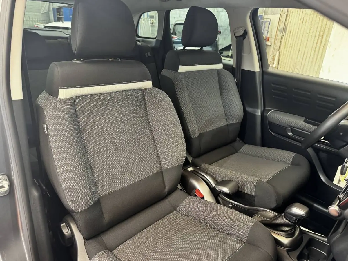 Vue intérieure côté avant droit montrant les sièges tissu gris foncé et noir de la Citroën C3 2019 Shine.