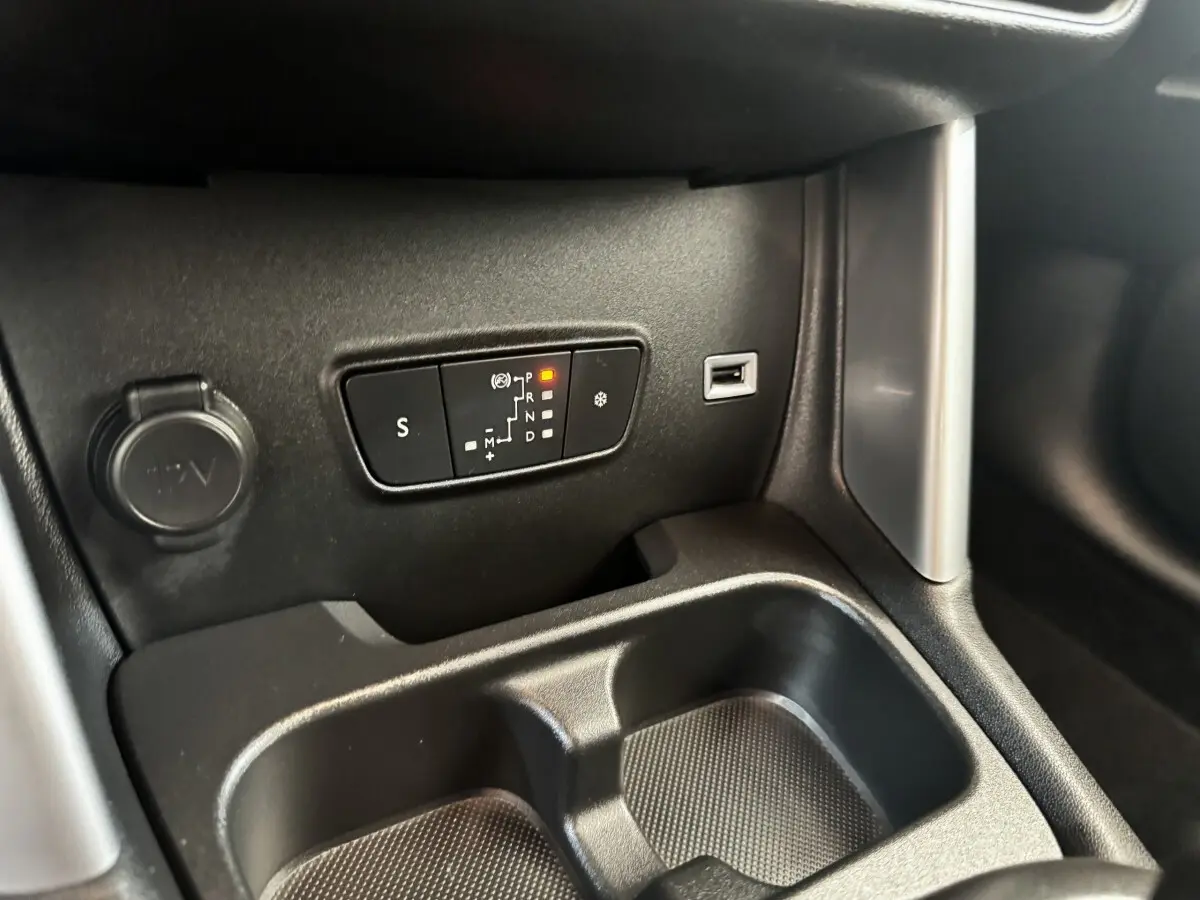 Détail intérieur de la console centrale de la Citroën C3 gris foncé, avec commandes de boîte automatique et prise 12V visible.