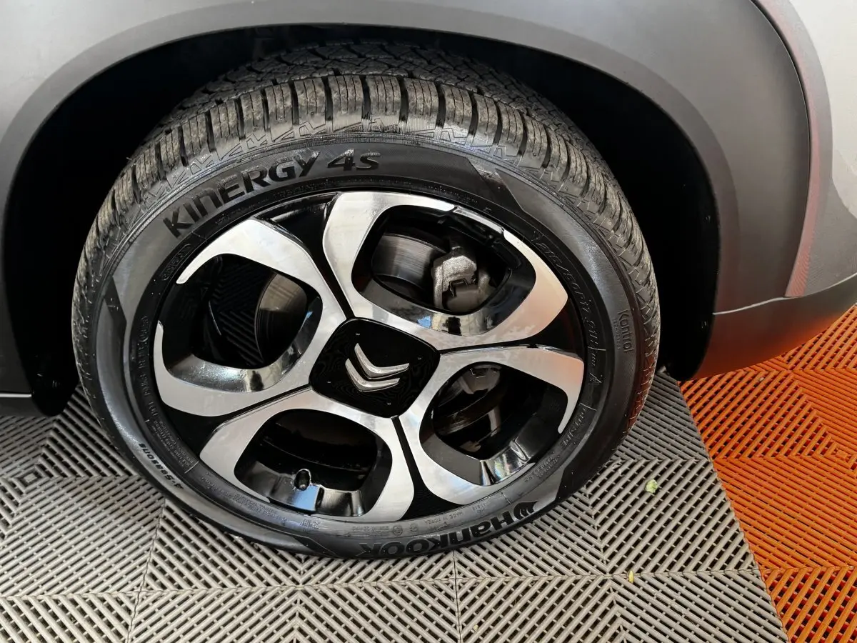 Gros plan sur la roue avant droite gris foncé de la Citroën C3 avec jante alliage bicolore et logo Citroën central.