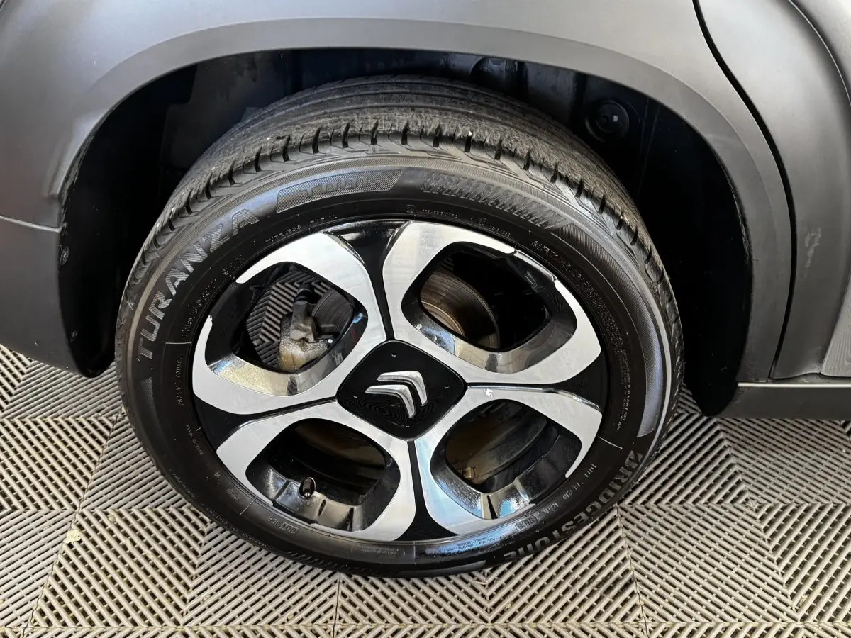 Gros plan sur la roue avant droite d'une Citroën C3 gris foncé avec jante alliage bicolore et logo Citroën central.