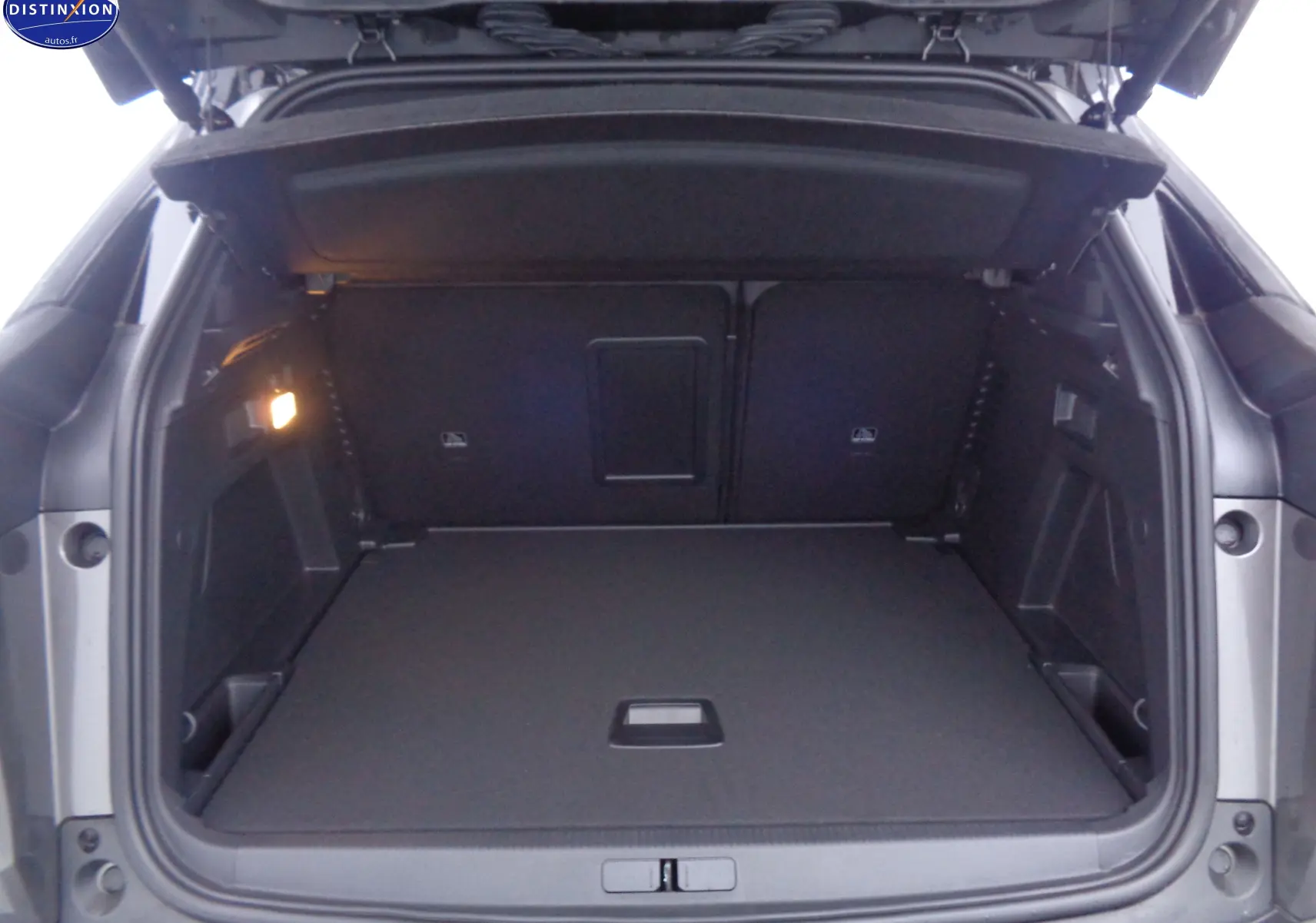 Coffre ouvert du Peugeot 3008 gris platinium métal, vue arrière montrant un espace de chargement spacieux et bien éclairé.