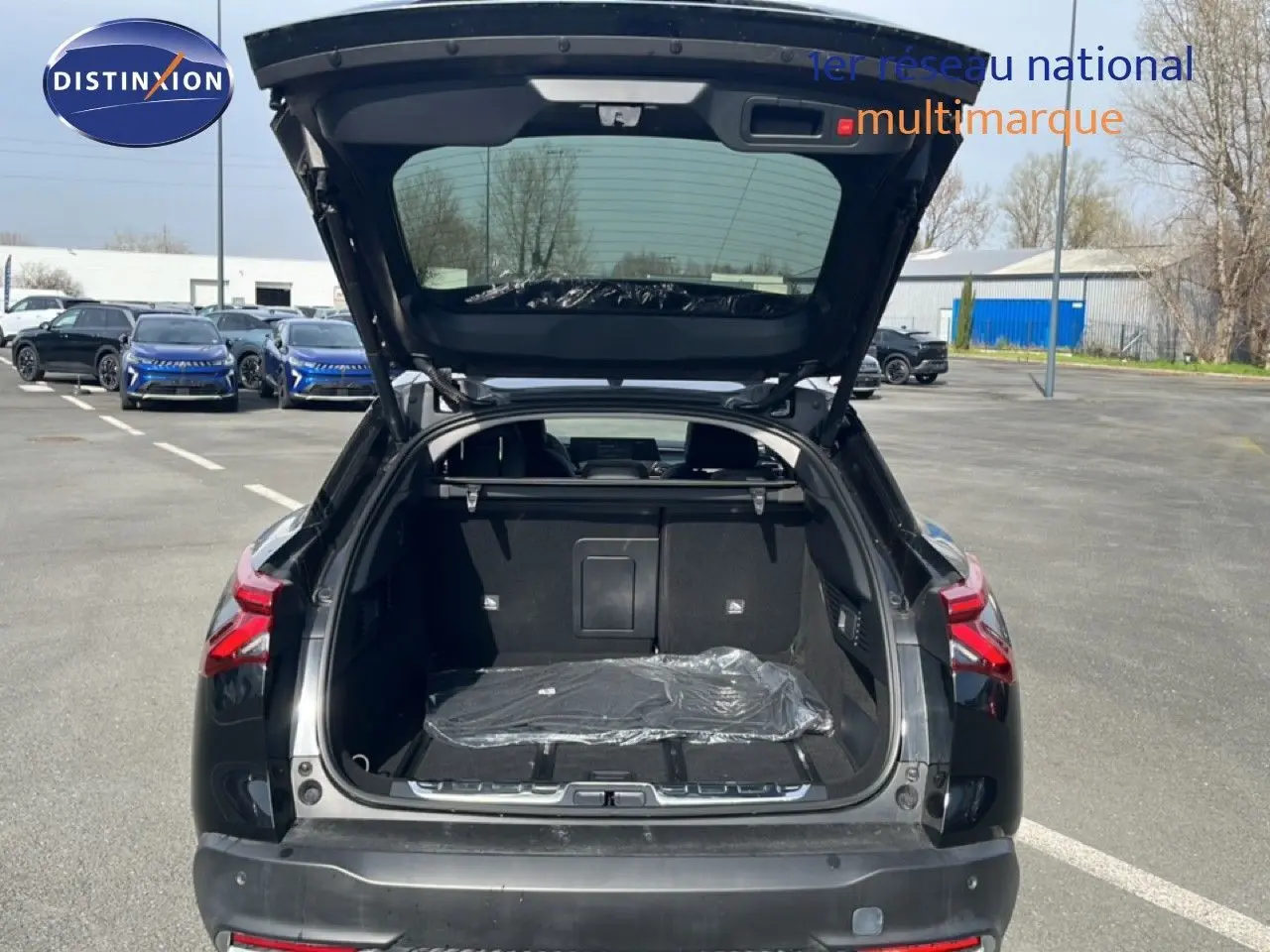 Vue arrière ouverte du coffre d'une Citroën C5 X noire métal 2023, soulignant son espace de chargement généreux.