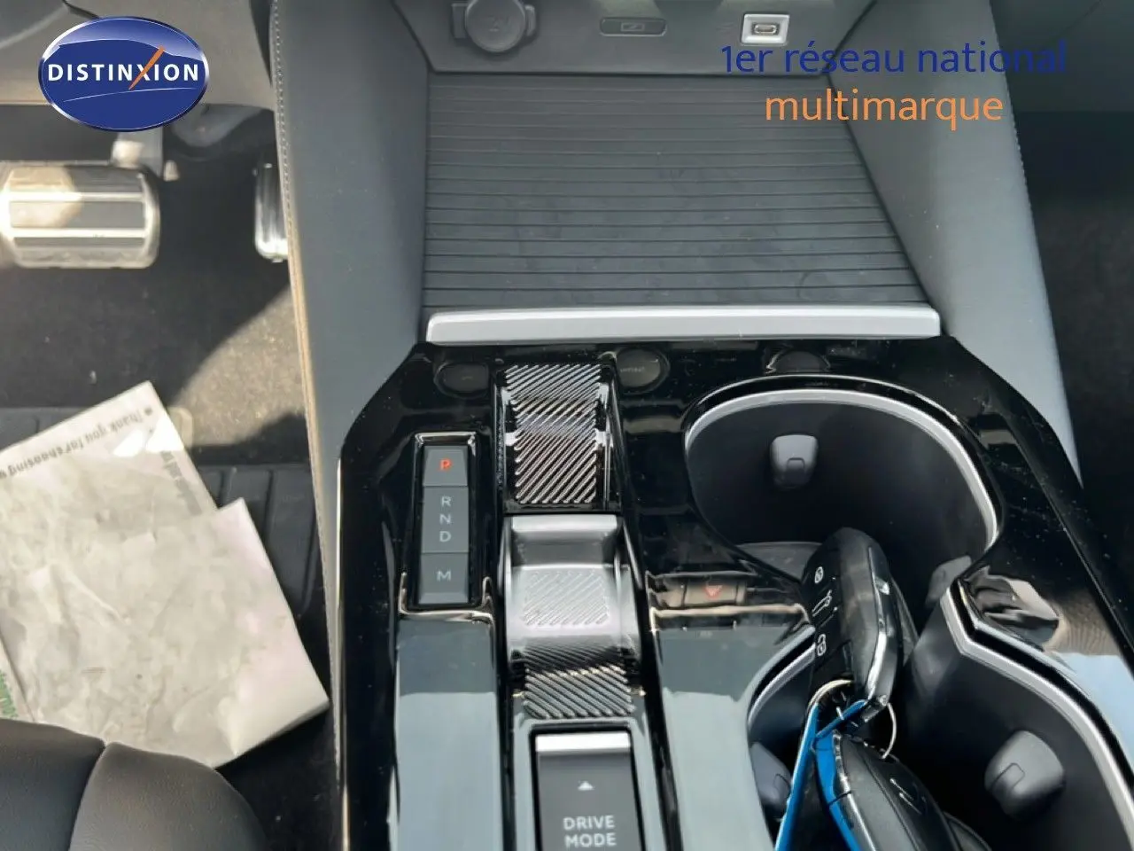 Vue rapprochée de la console centrale noire brillante de la Citroën C5 X 2023, avec levier de vitesses et porte-gobelets.