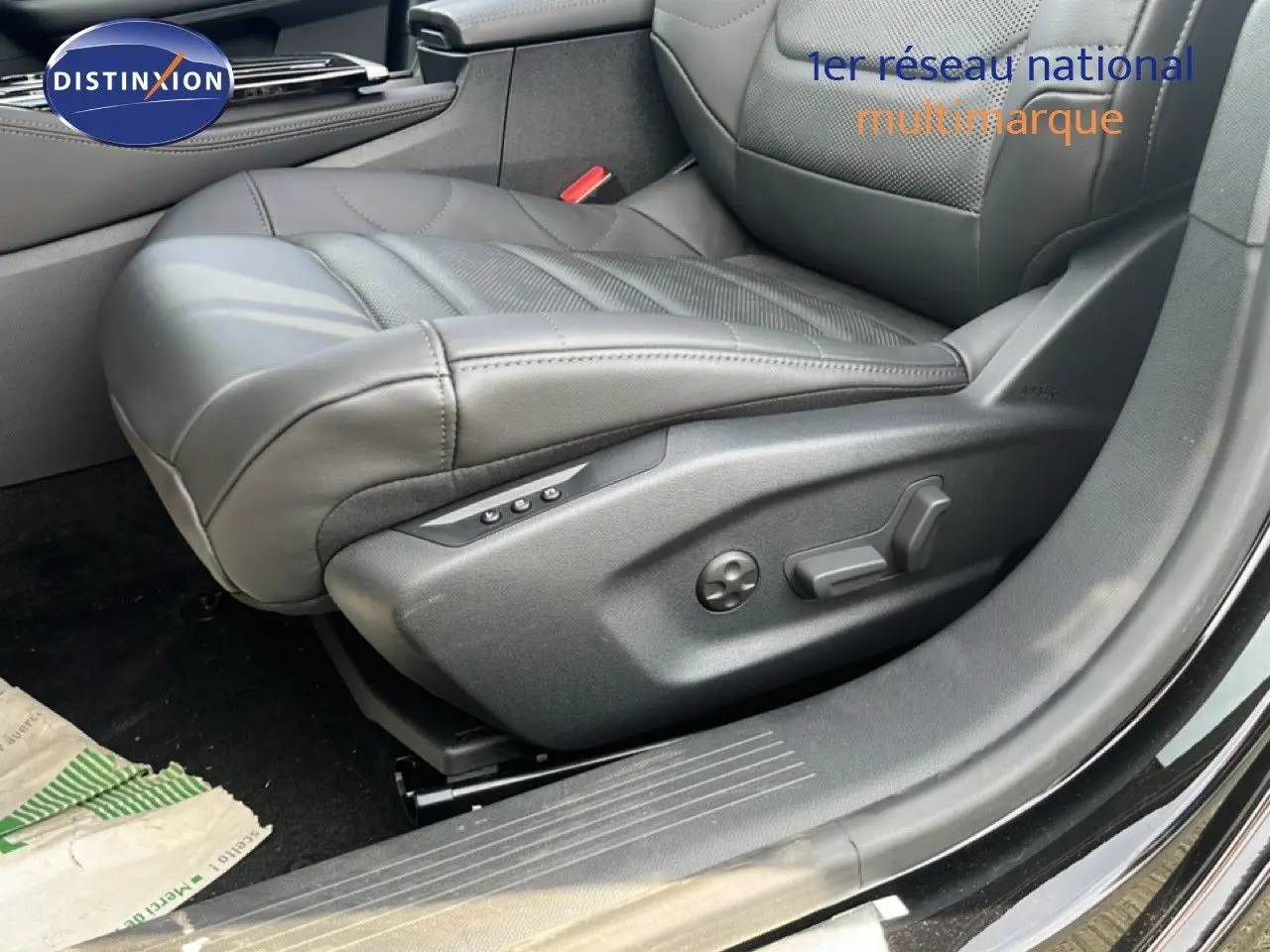 Gros plan sur le siège conducteur en cuir noir de la Citroën C5 X 2023, avec réglages électriques visibles, porte ouverte côté gauche.