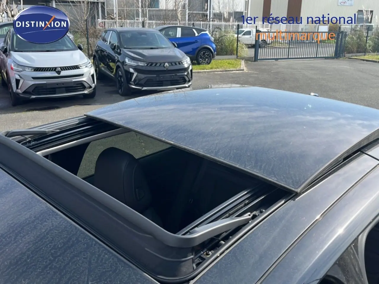 Toit ouvrant ouvert en vue plongeante sur le toit noir métal de la Citroën C5 X 2023, intérieur partiellement visible.