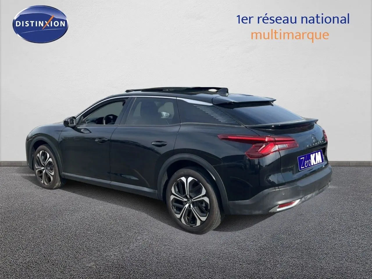Vue 3/4 arrière gauche d'une Citroën C5 X noire métal 2023 avec jantes bi-ton et toit panoramique.