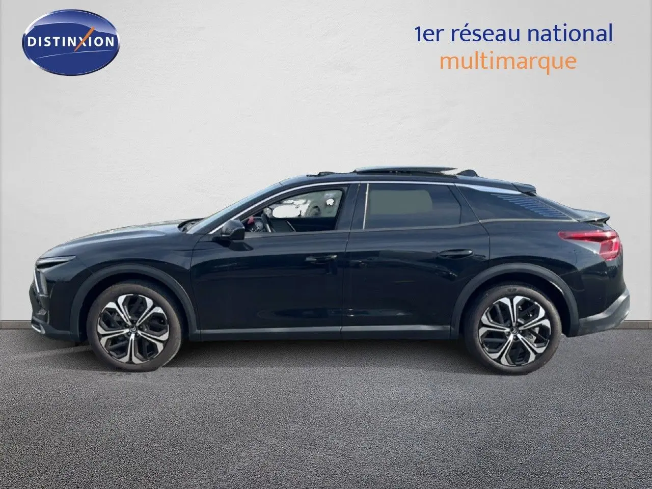 Profil droit d'une Citroën C5 X noire métal 2023, avec jantes bi-ton et toit panoramique ouvert.