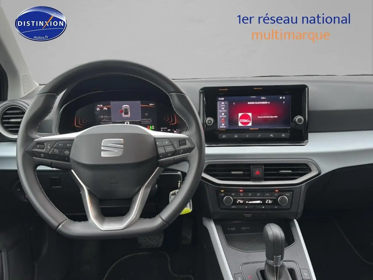 Vue frontale de l'intérieur du SEAT Arona noir minuit 2025, volant cuir méplat et écran tactile central visible.