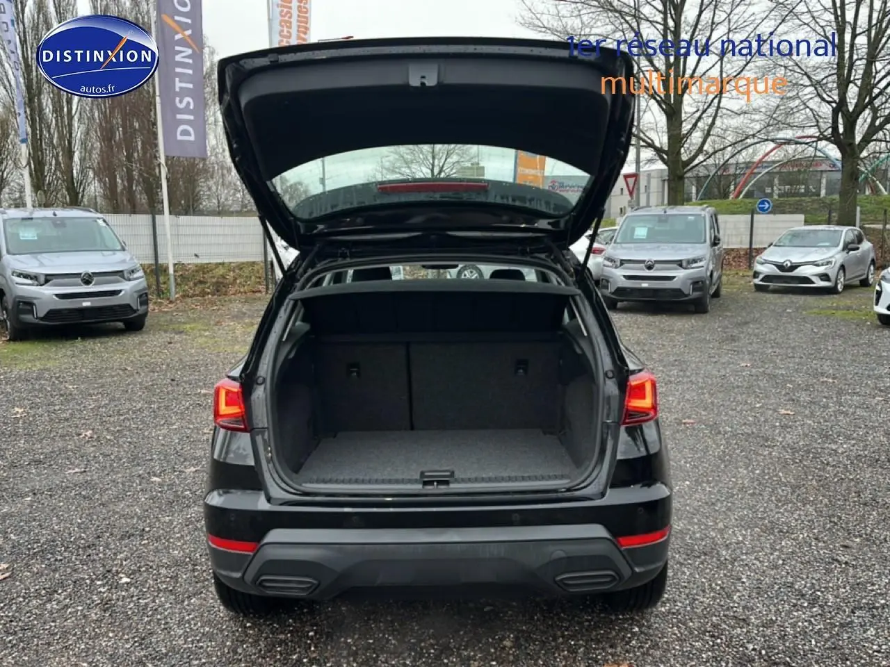 Vue arrière d'un SEAT Arona noir minuit 2025 avec coffre ouvert sur un parking extérieur.