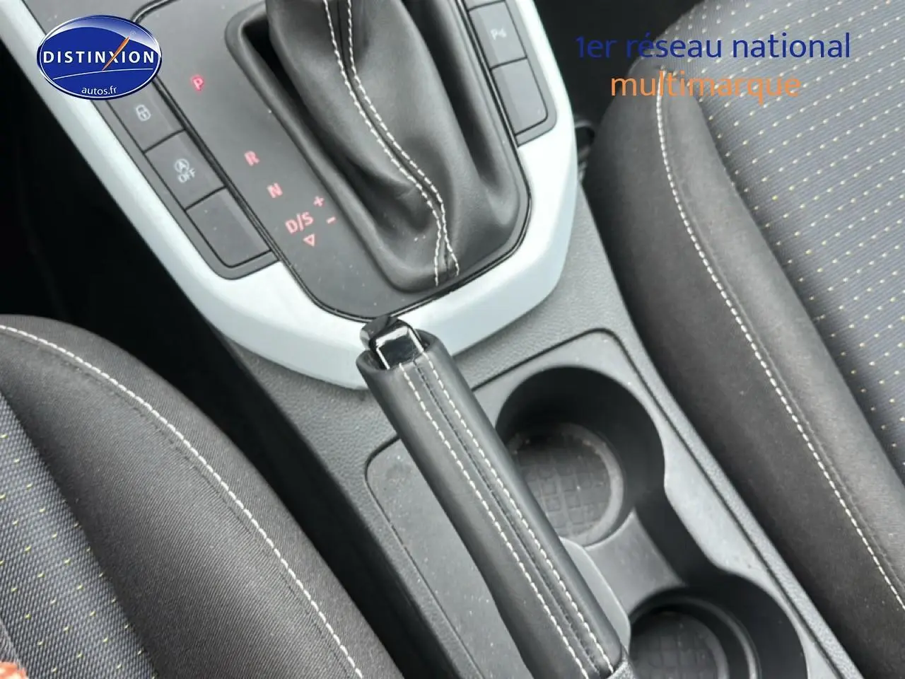 Vue rapprochée de la console centrale avec levier de frein à main cuir noir et sièges tissu gris du SEAT Arona 2025.