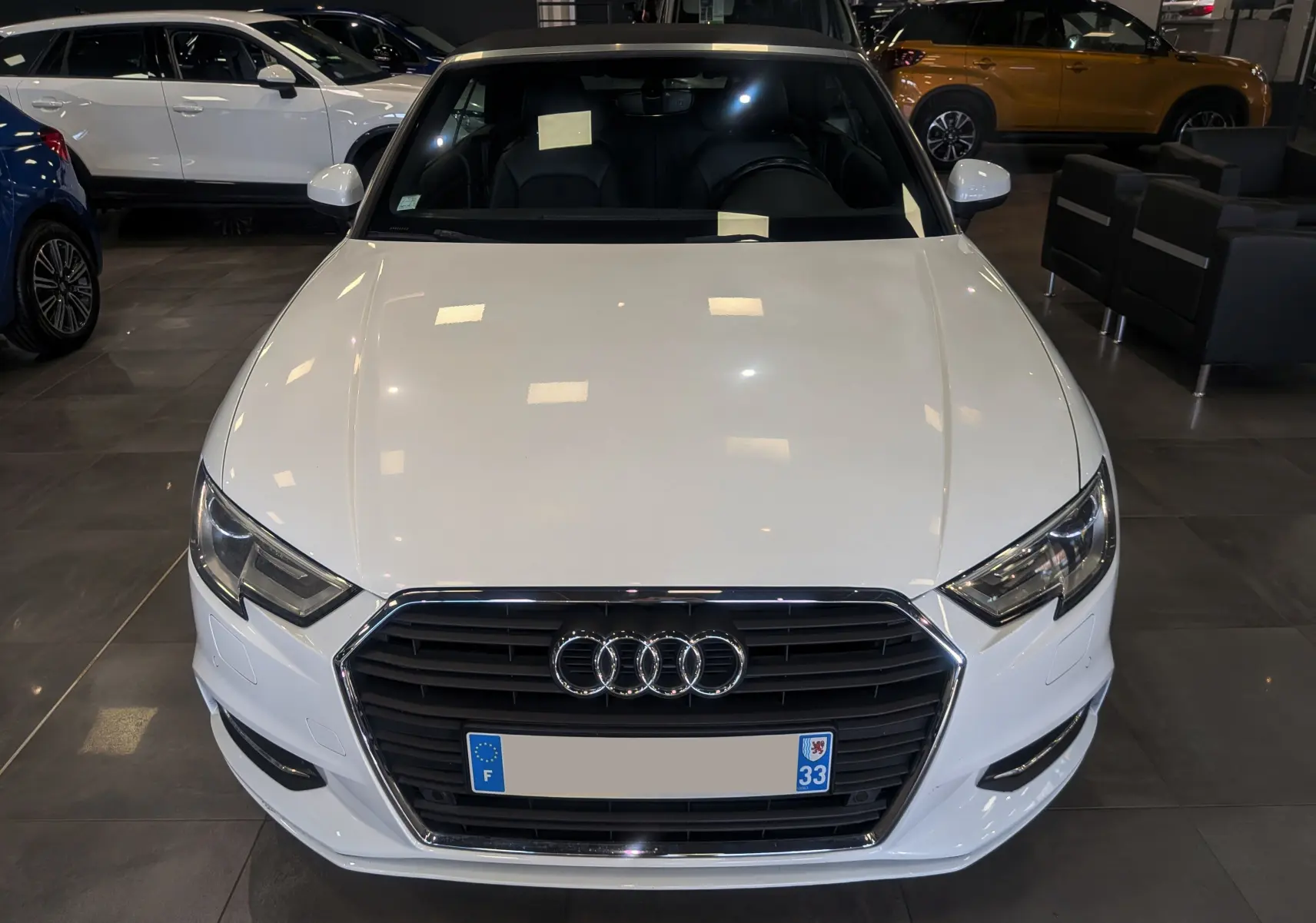 Vue avant d'une Audi A3 Cabriolet blanche 2017 avec calandre noire et intérieur cuir noir visible en showroom.