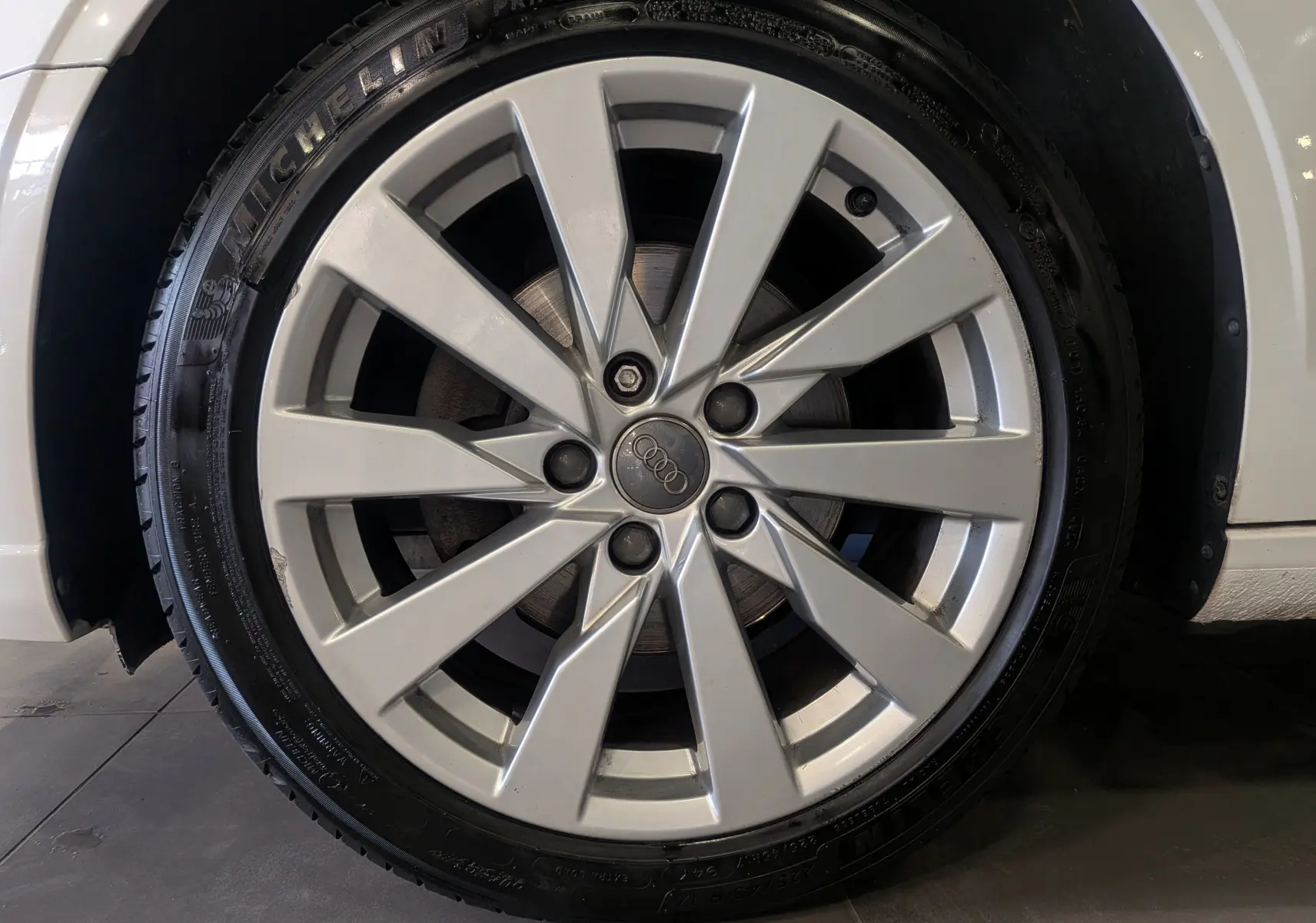 Gros plan sur la jante alliage argentée de l'Audi A3 Cabriolet blanc, mettant en valeur le logo Audi au centre.