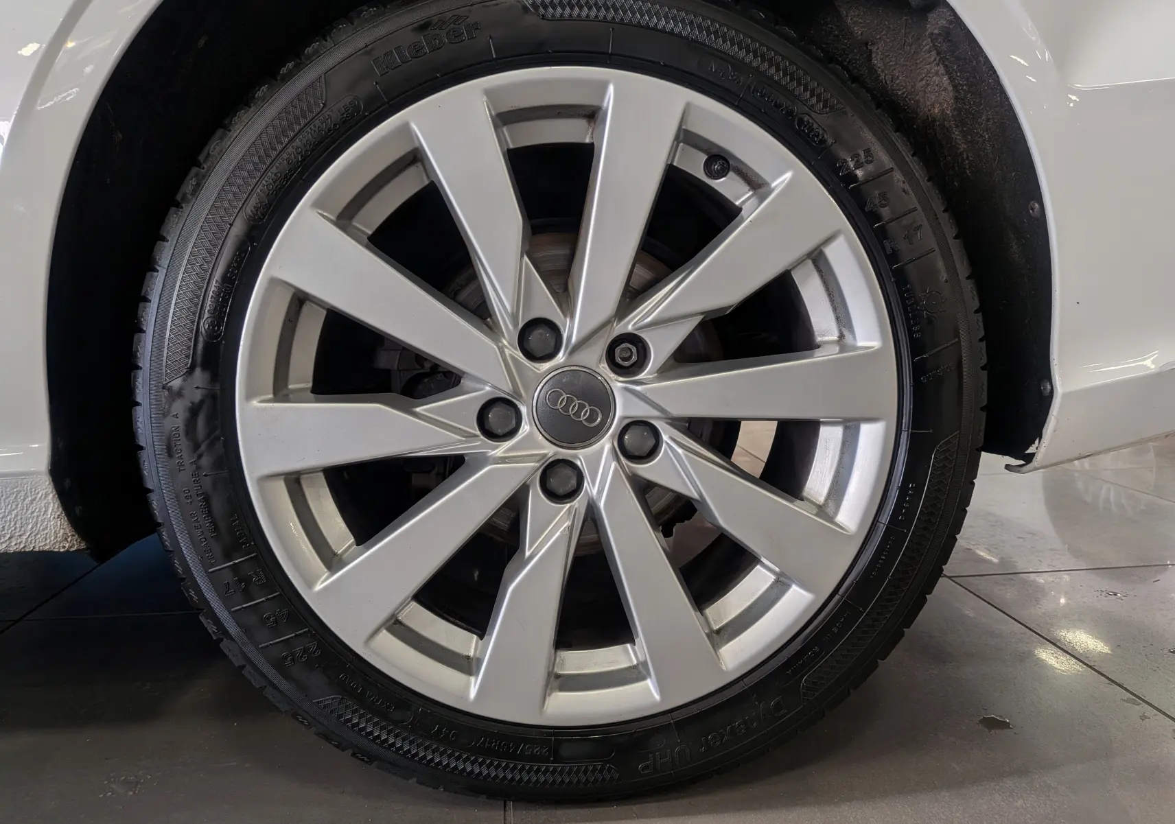 Gros plan sur la jante alliage argentée de l'Audi A3 Cabriolet blanc, mettant en valeur le logo Audi central.